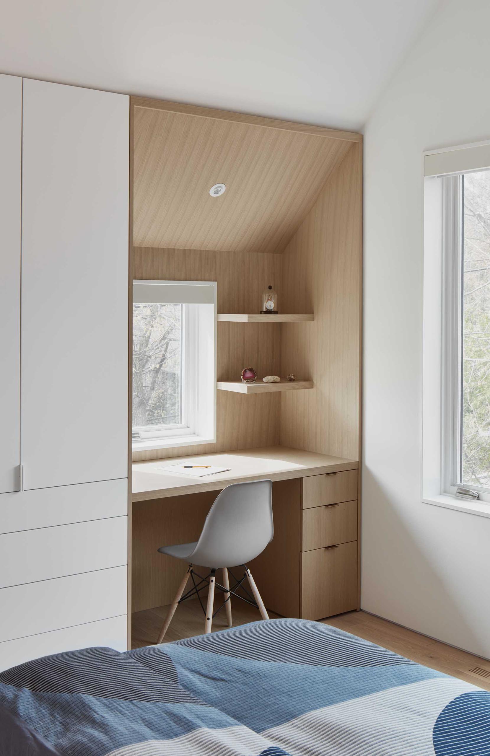 This modern bedroom includes a  custom designed desk that's lined with wood, and matches the angle of the ceiling.