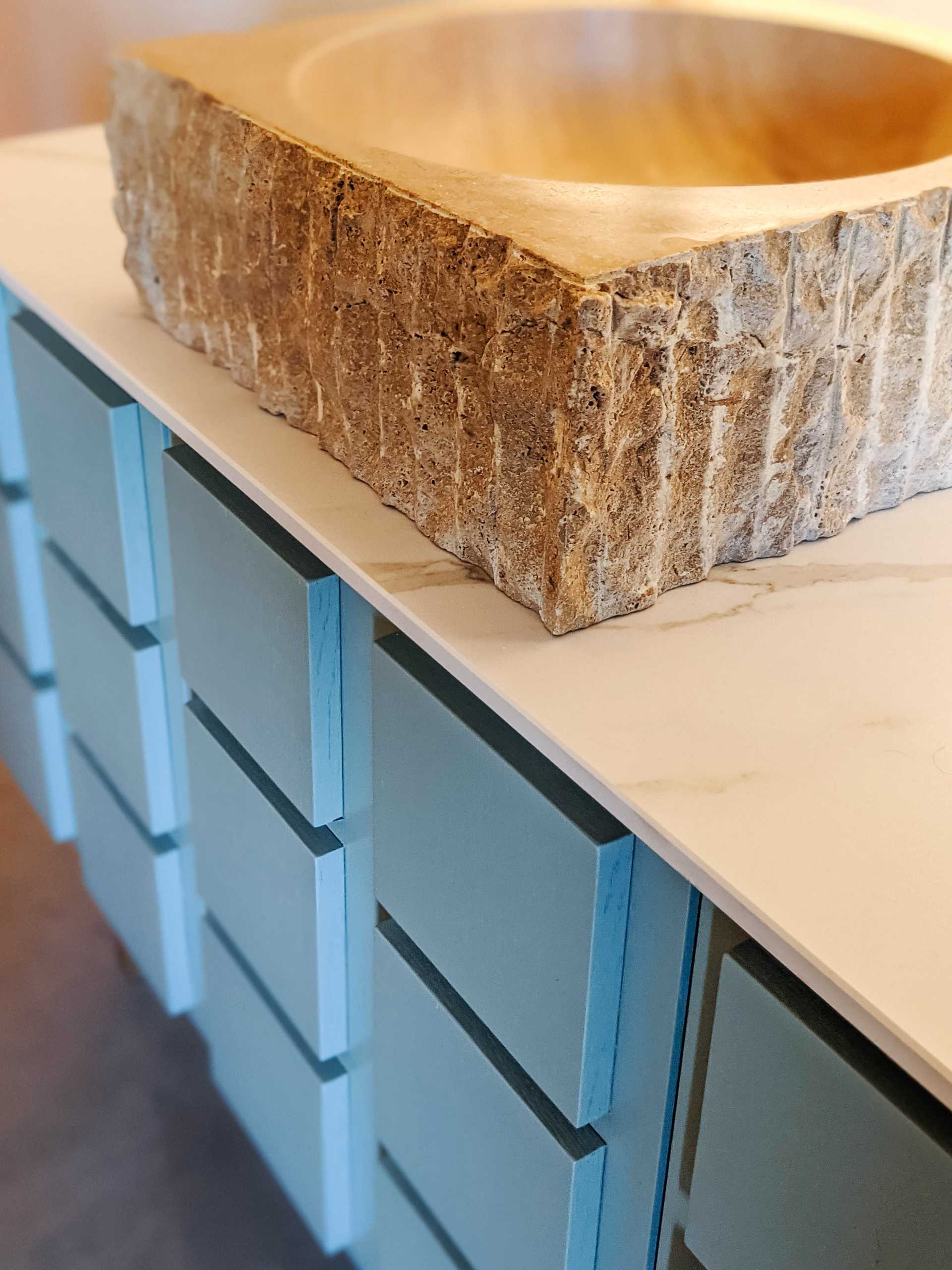 A contemporary blue bathroom vanity with a carved sink.