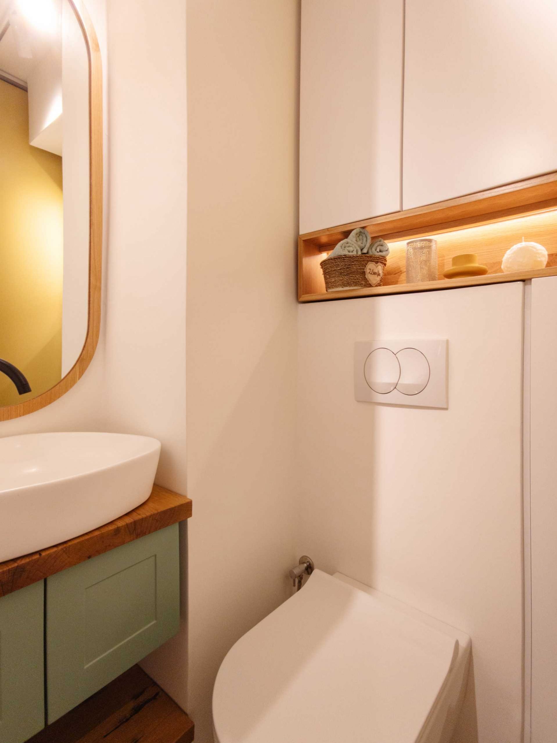 In this contemporary bathroom, green and yellow have been used as accents, while the wood framed mirror matches the shelving niche.