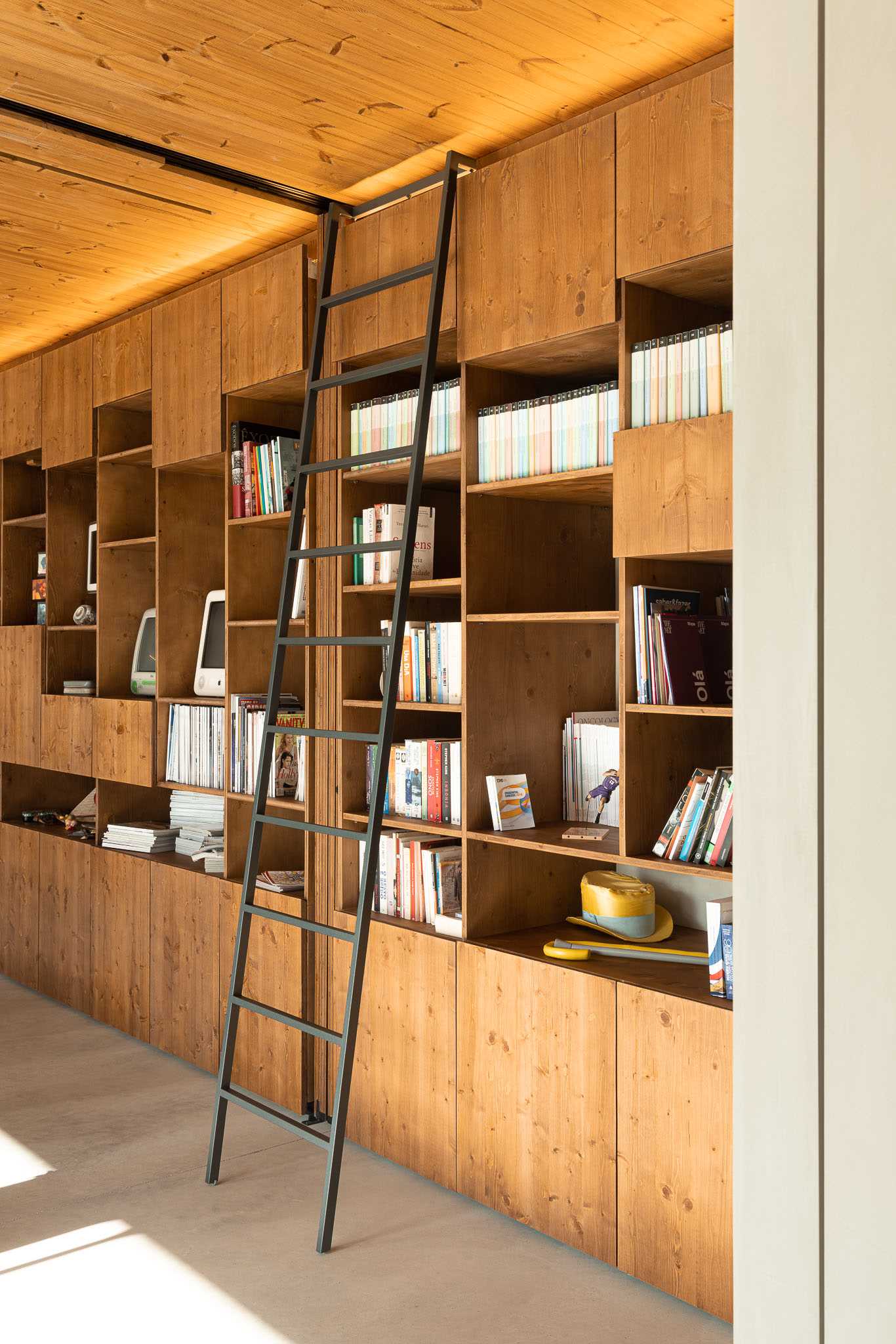 A modern wood bookshelf with a ladder.