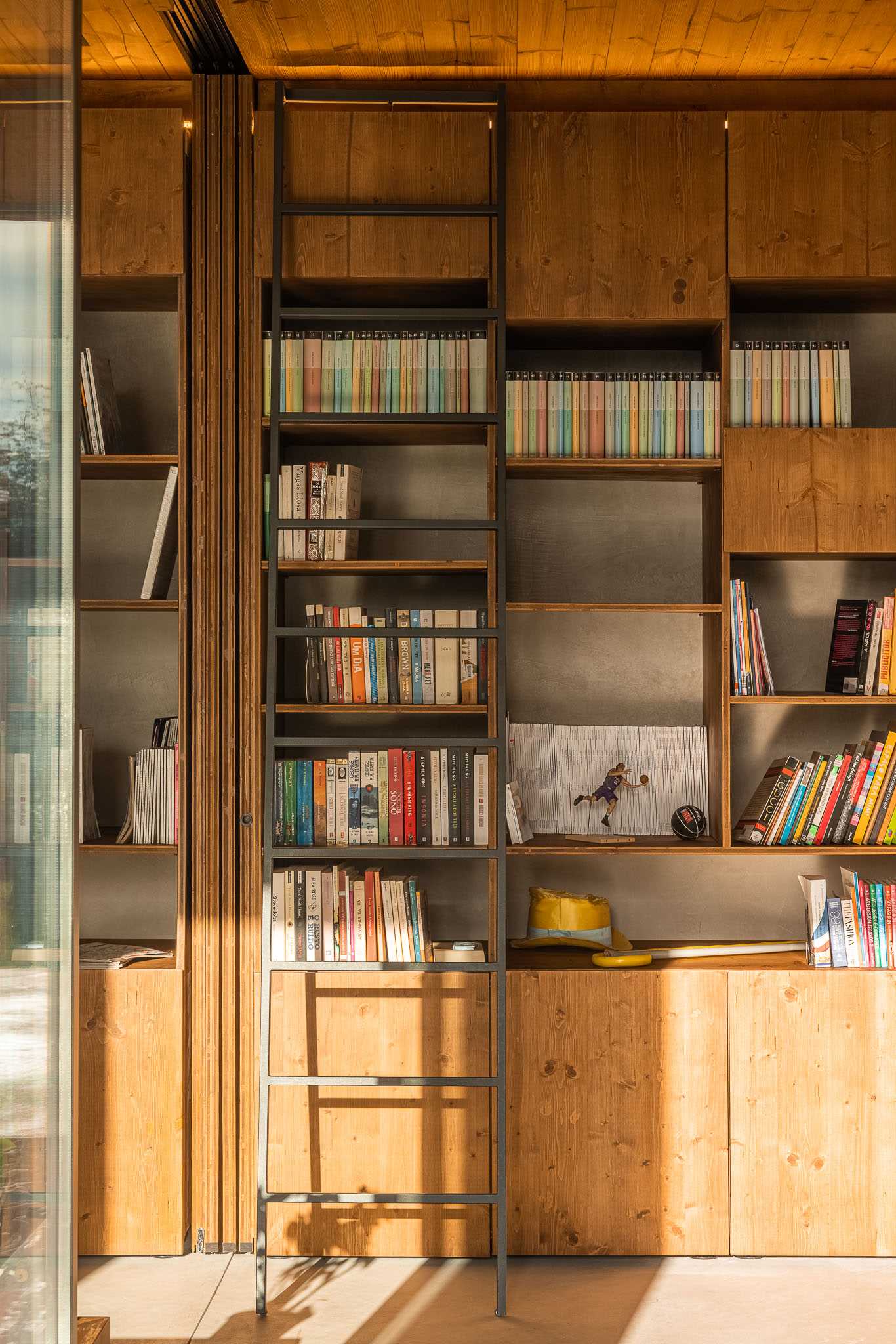 A modern wood bookshelf with a ladder.