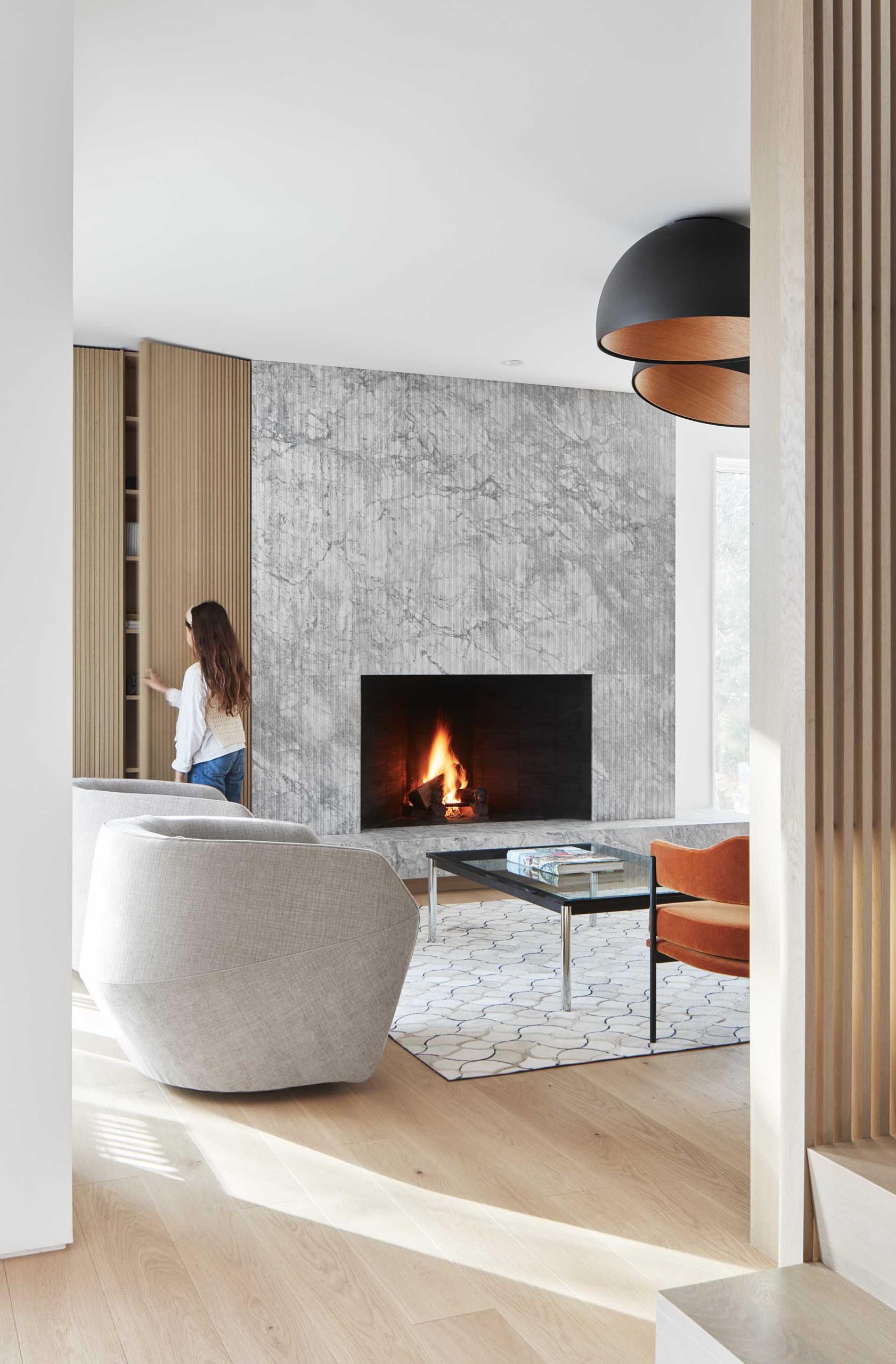 Next to this grey quartz fireplace surround is a wood slat detail that hides a storage cabinet.