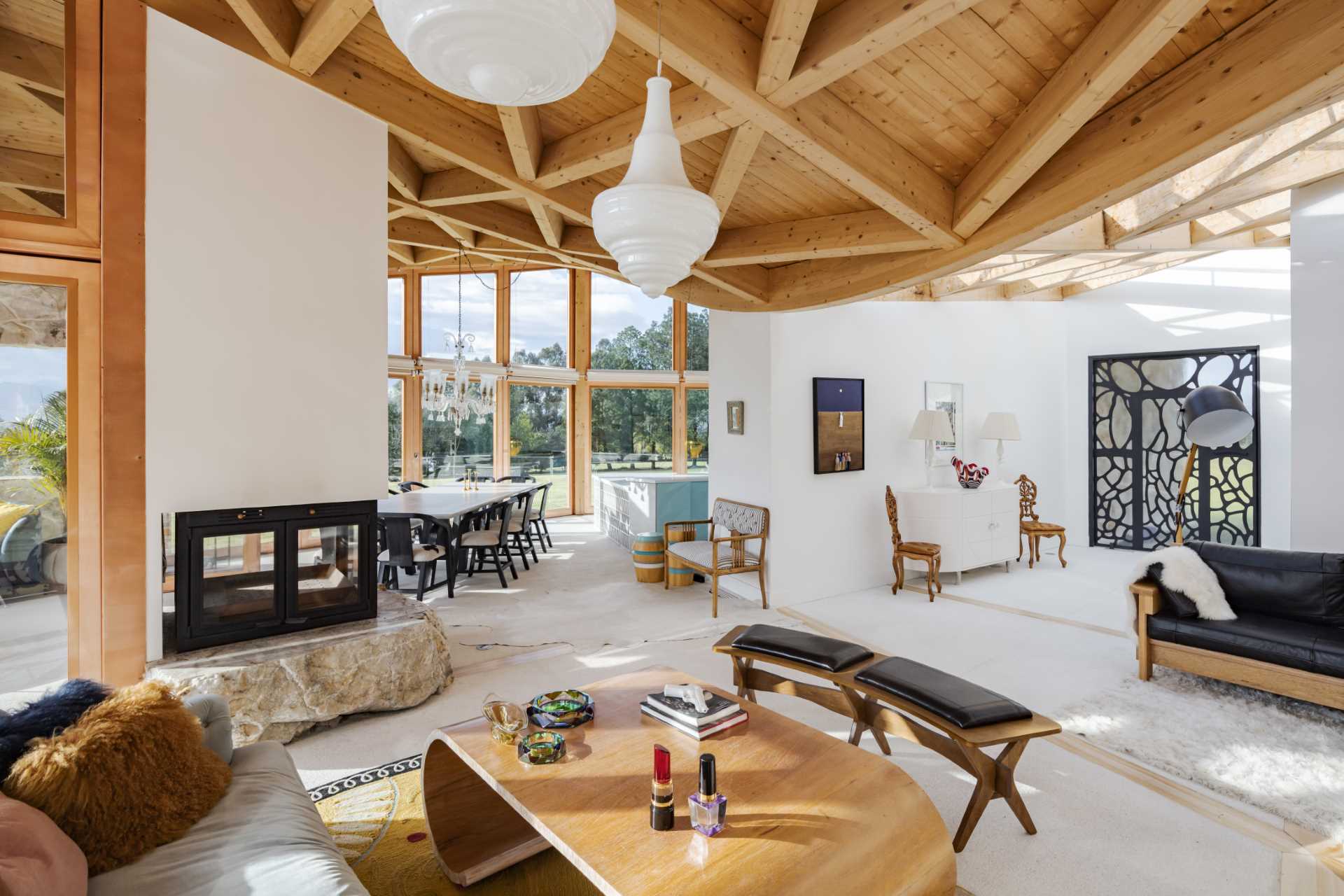 This modern living room showcases walls of glass that flood the interior with natural light, a double-sided fireplace, and the exposed wood ceiling.