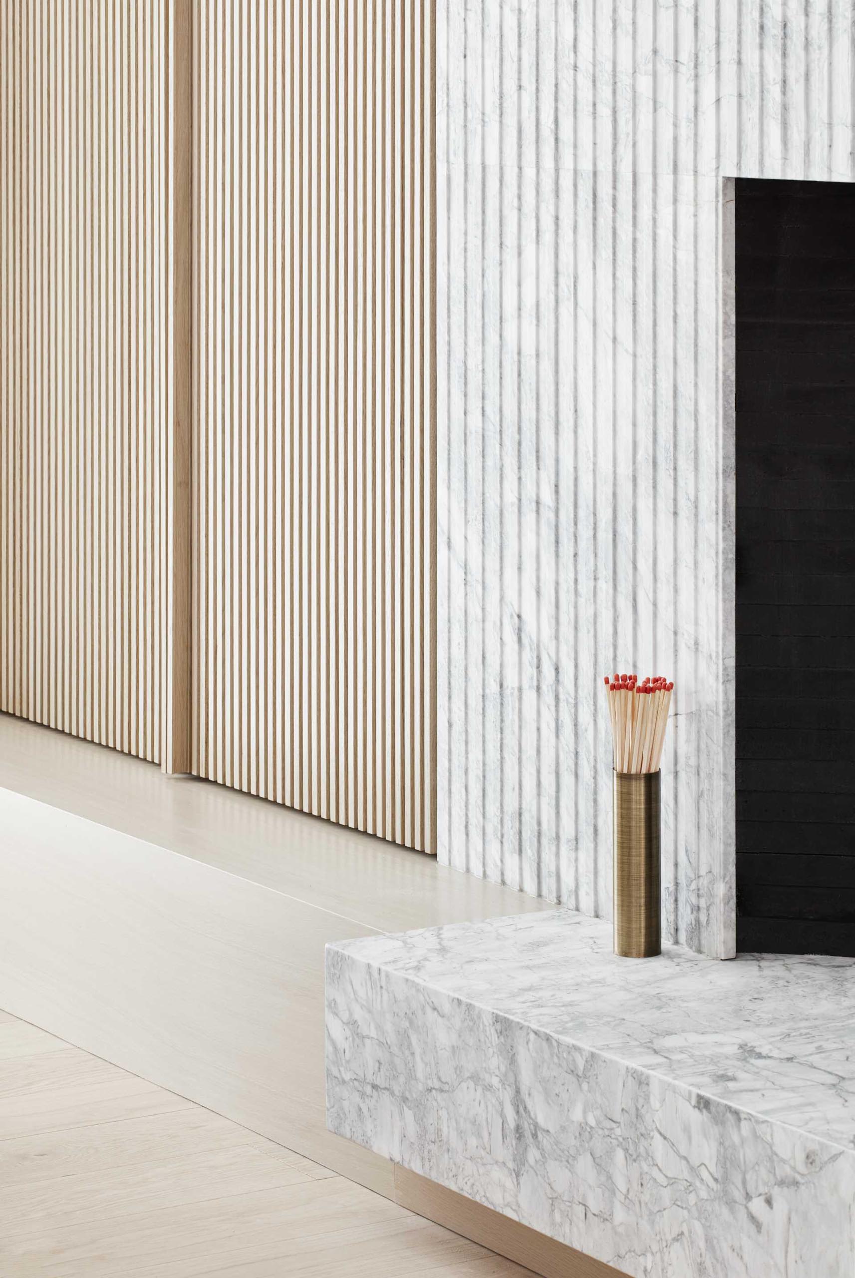 Next to this grey quartz fireplace surround is a wood slat detail that hides a storage cabinet.