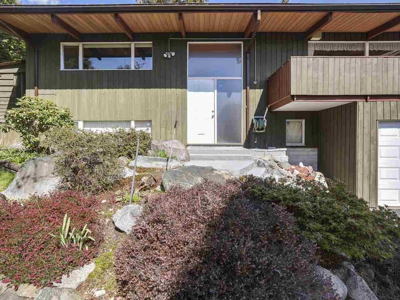 A mid-century modern home with faded green paint and white framed windows.