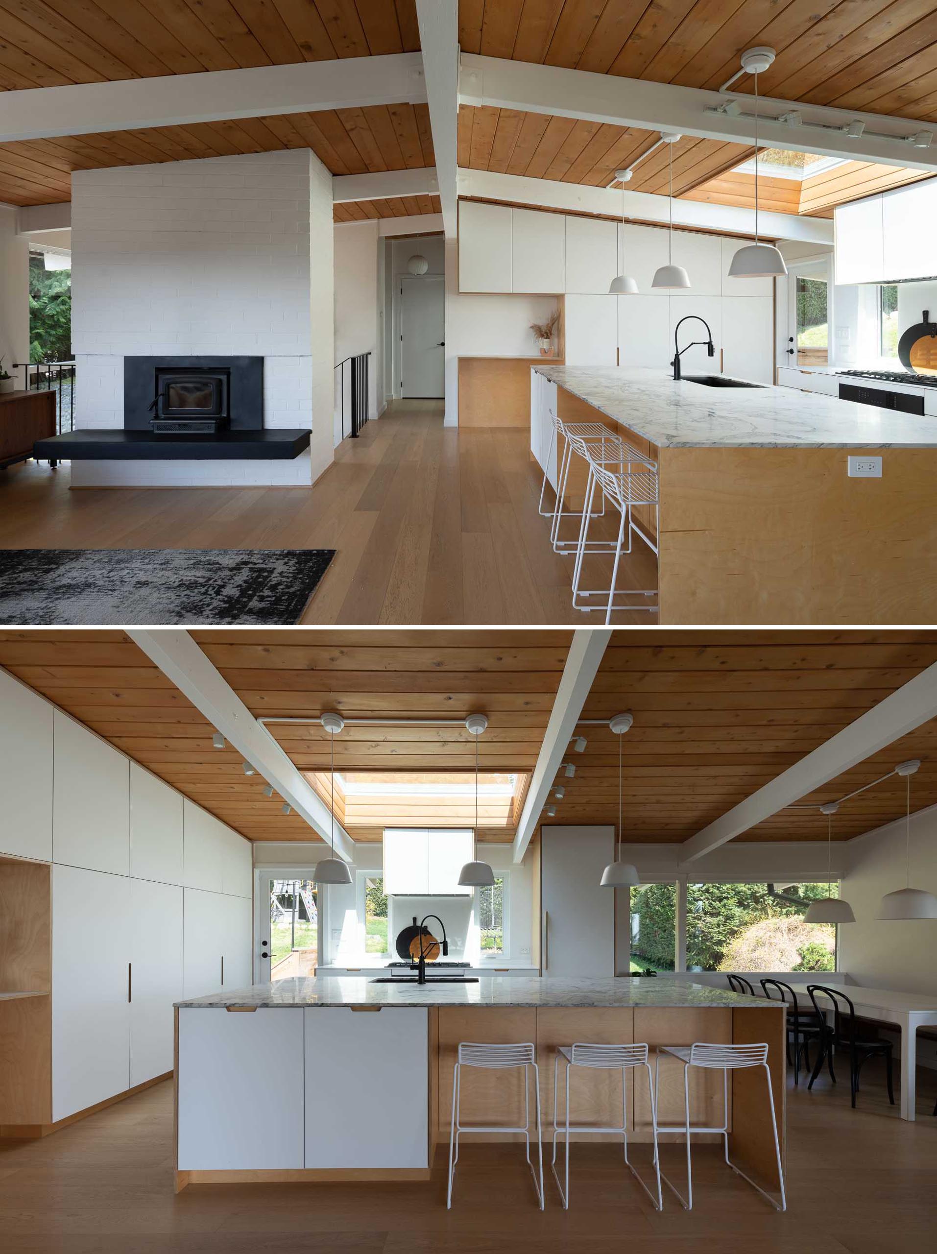 A remodeled kitchen with minimalist white cabinetry, and an oversized 10 foot by 5 foot marble topped kitchen island.