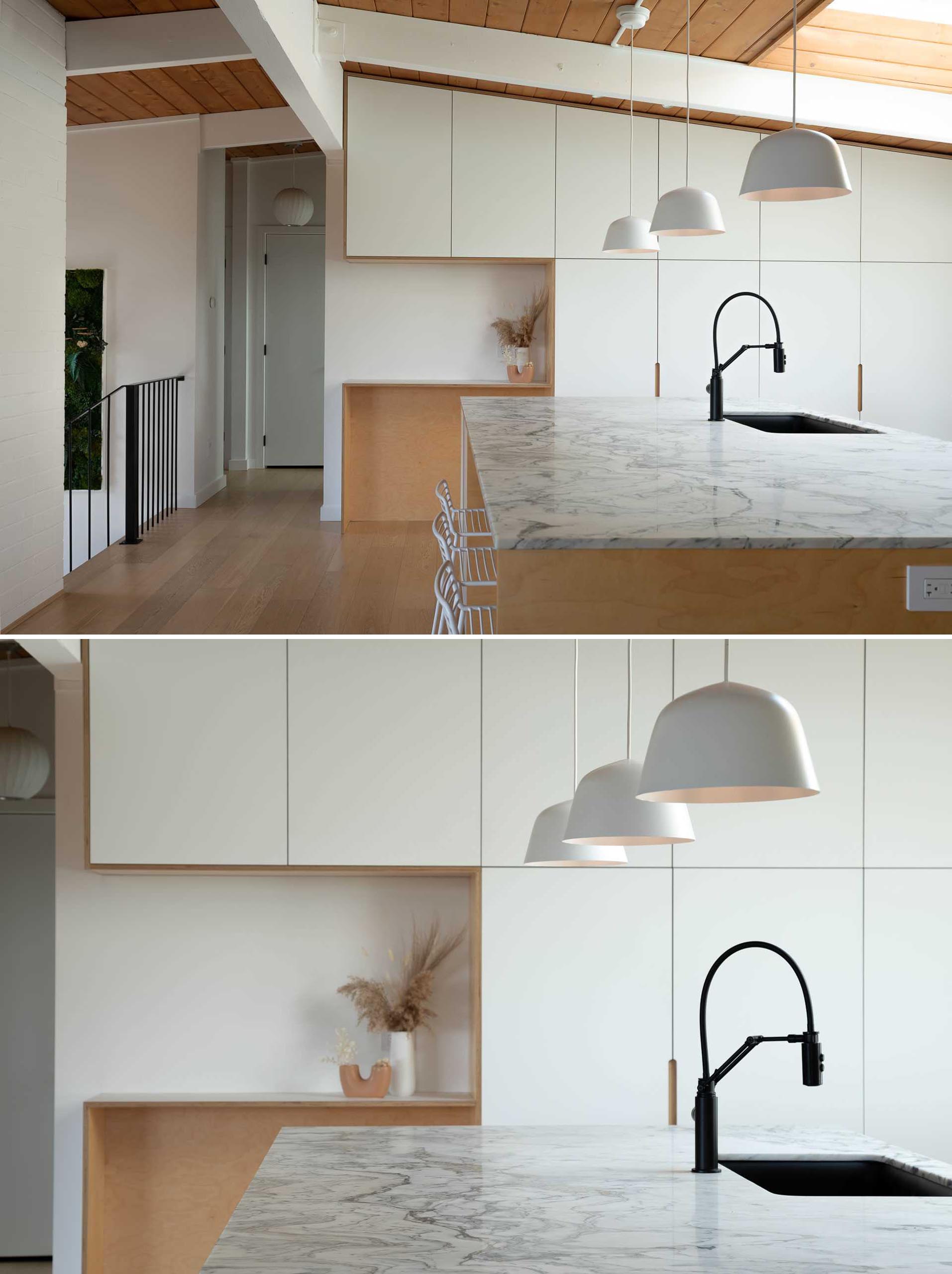 A remodeled kitchen with minimalist white cabinetry, and an oversized 10 foot by 5 foot marble topped kitchen island.