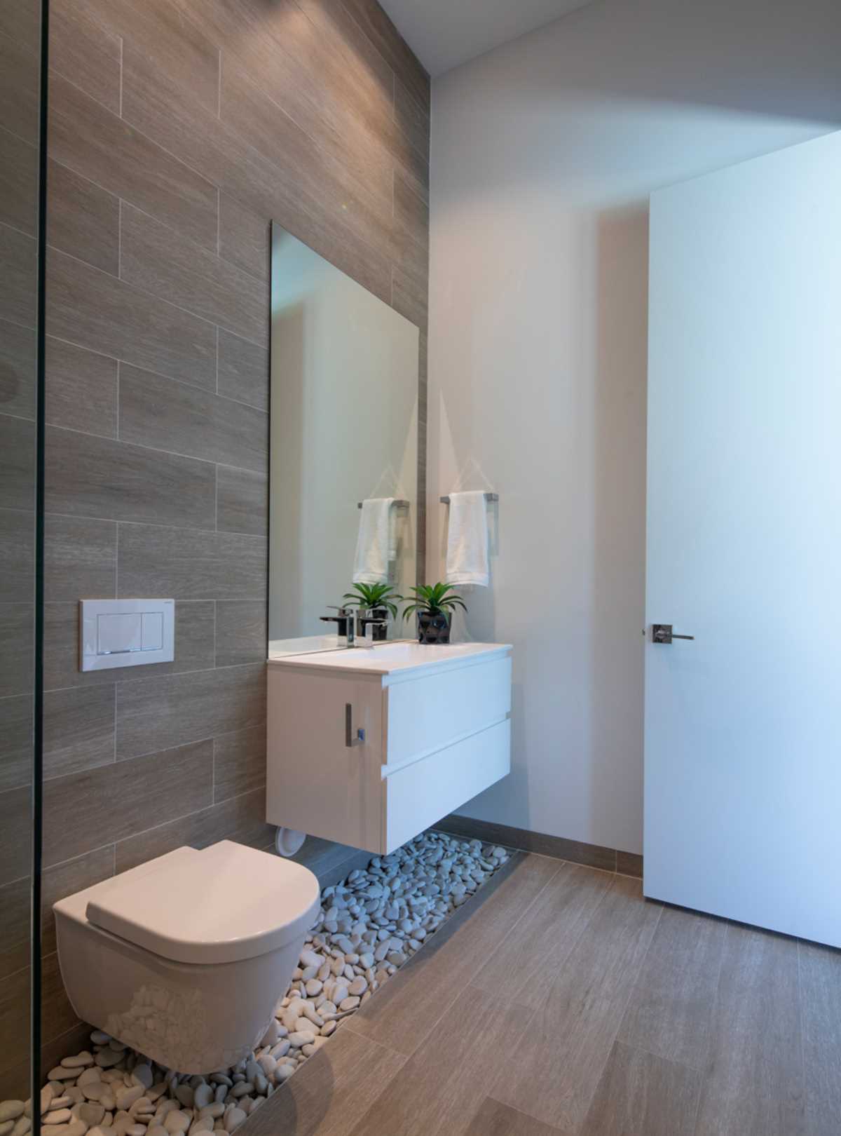 A contemporary bathroom that includes pebbles underneath the floating vanity.