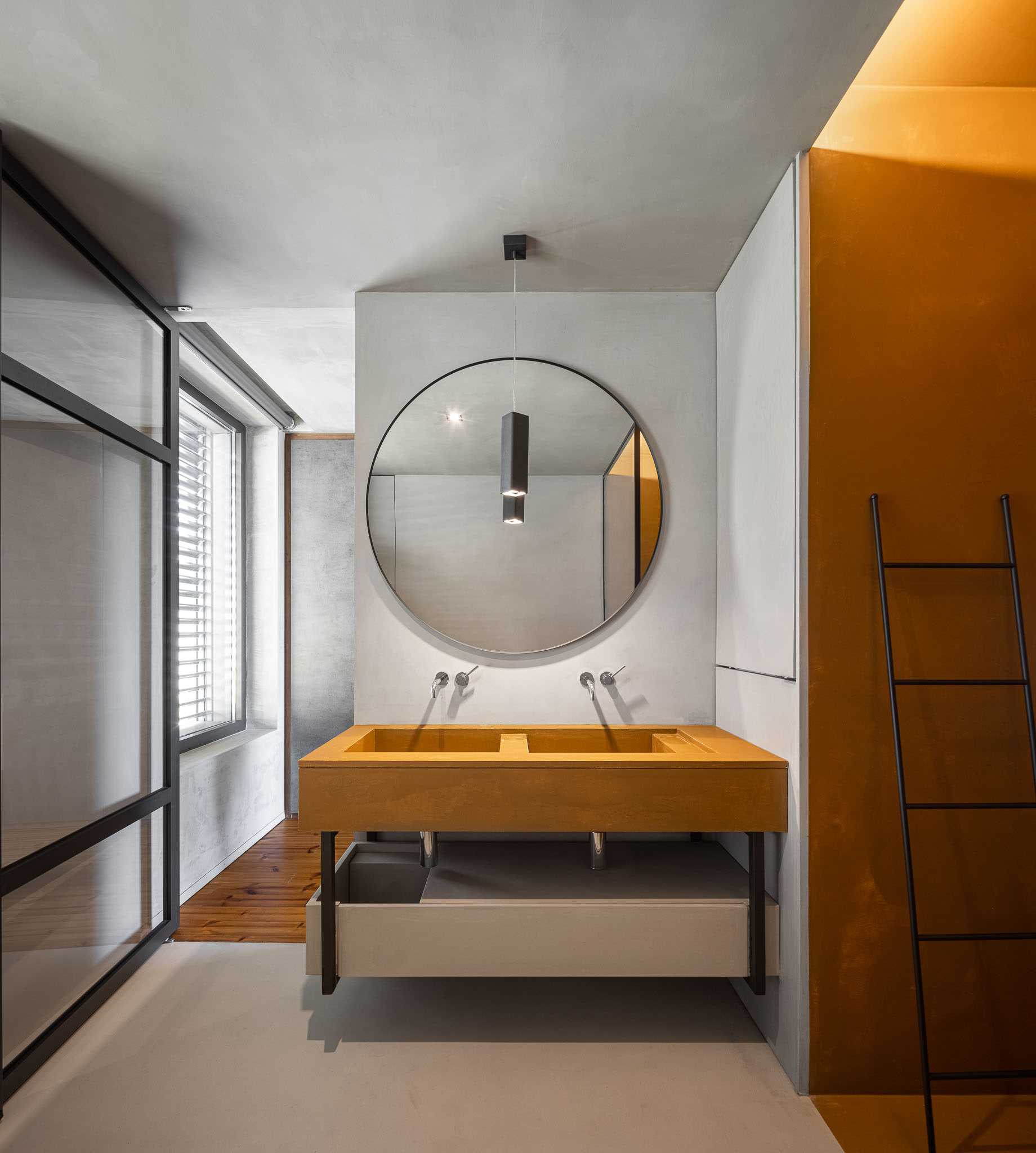 A modern bathroom with a double vanity and round mirror.
