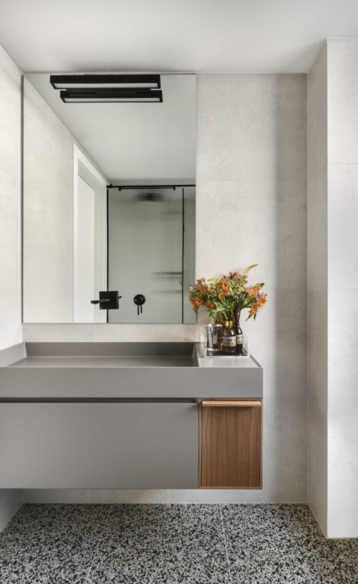 This modern bathroom includes a floating vanity with a muted gray finish, built-in sink, and a small wood accent.