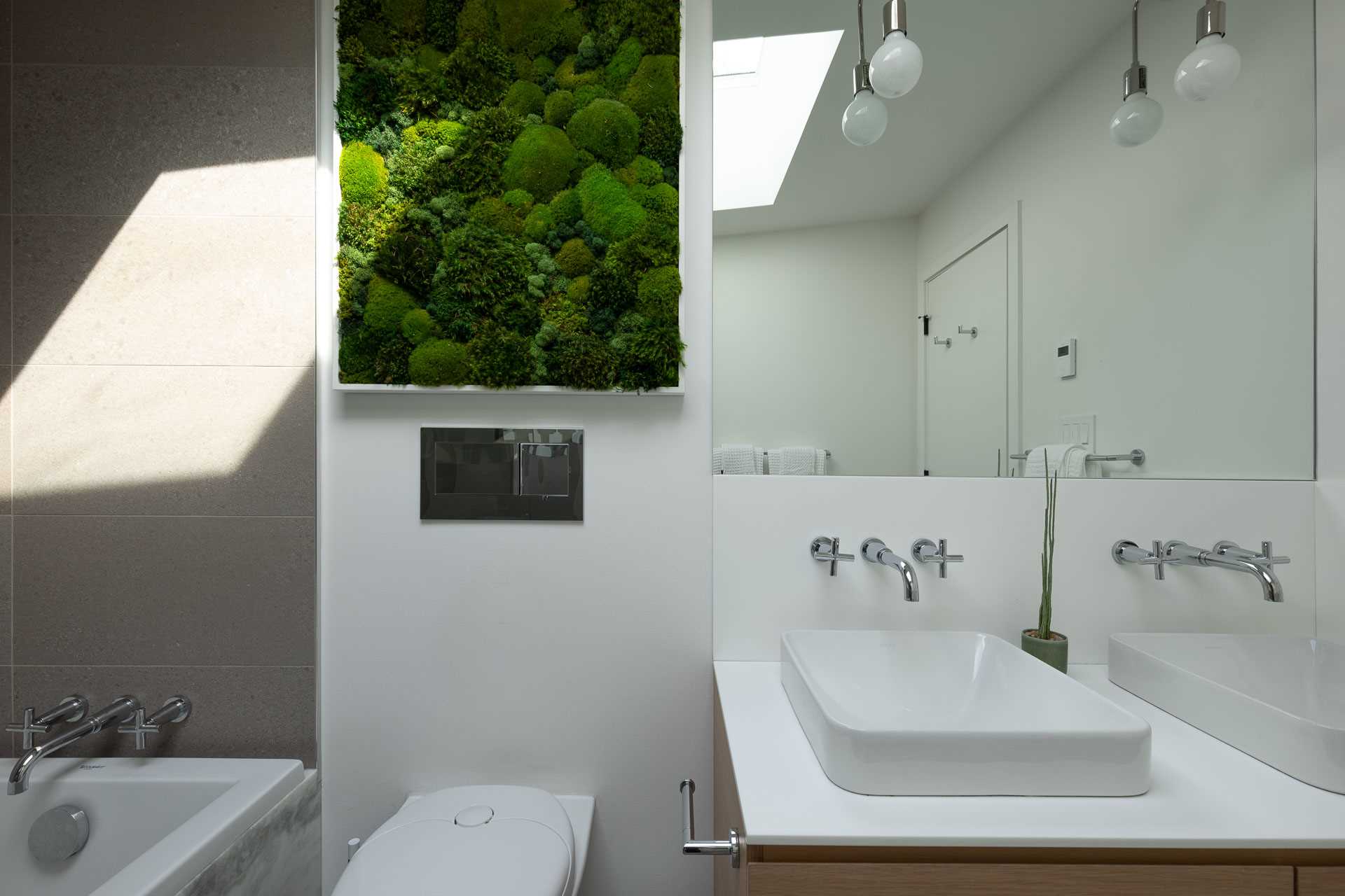 A modern bathroom with oversized tiles, and a simple white and wood vanity.