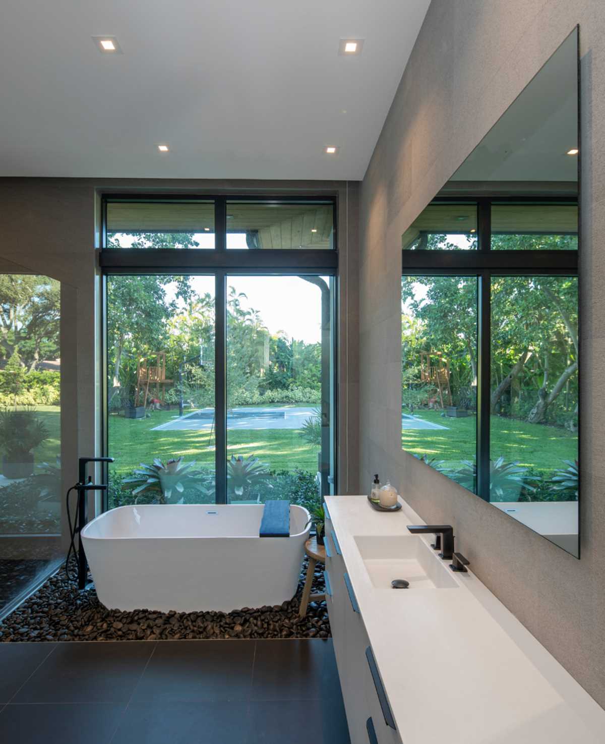 A contemporary bathroom that includes pebbles underneath the freestanding bathtub.