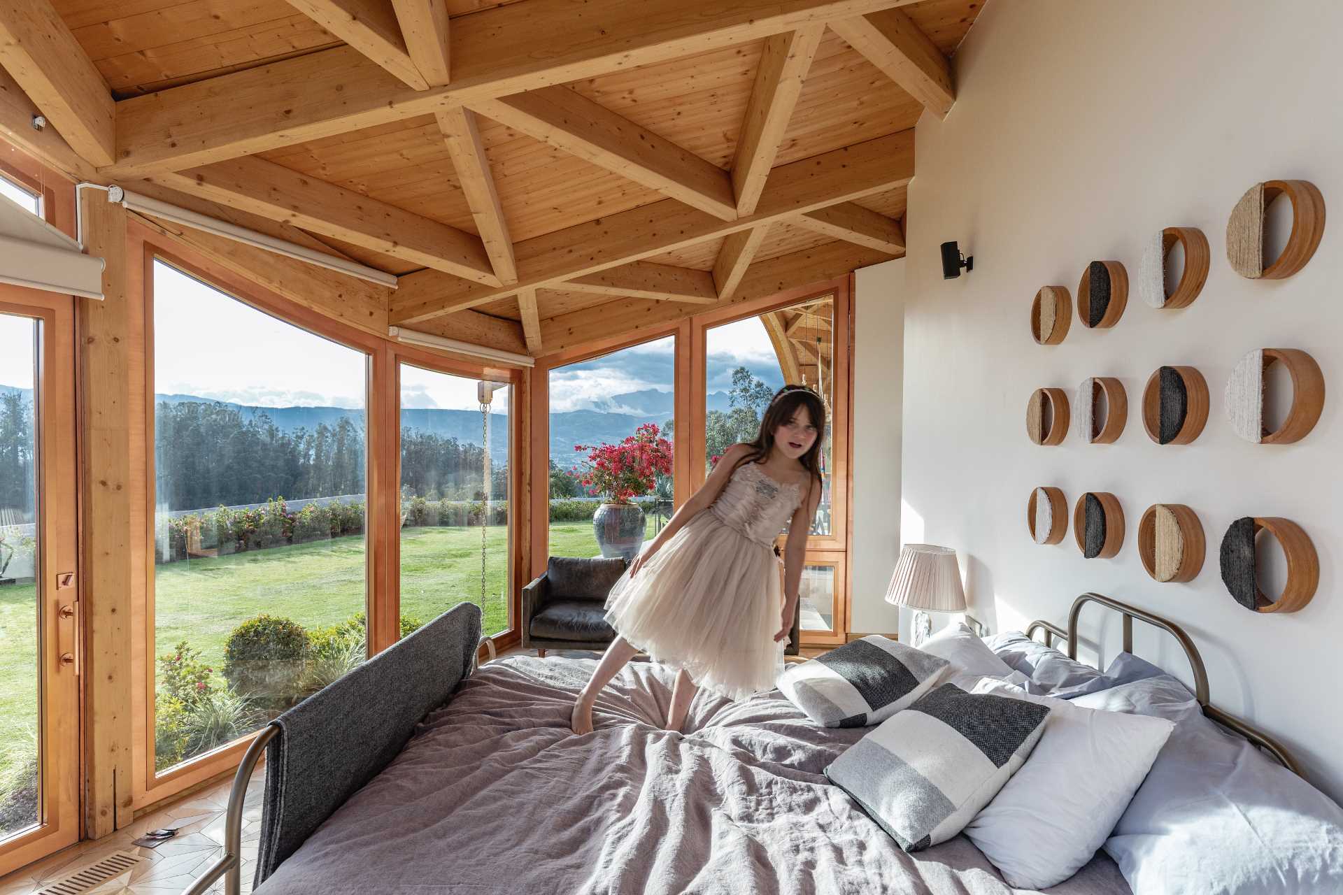 A bedroom with large windows and exposed wood ceiling.