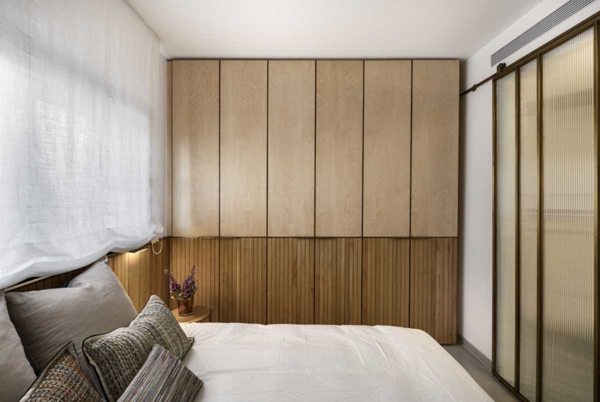 In this primary bedroom, a custom designed closet with a wood slat accent fills the wall.