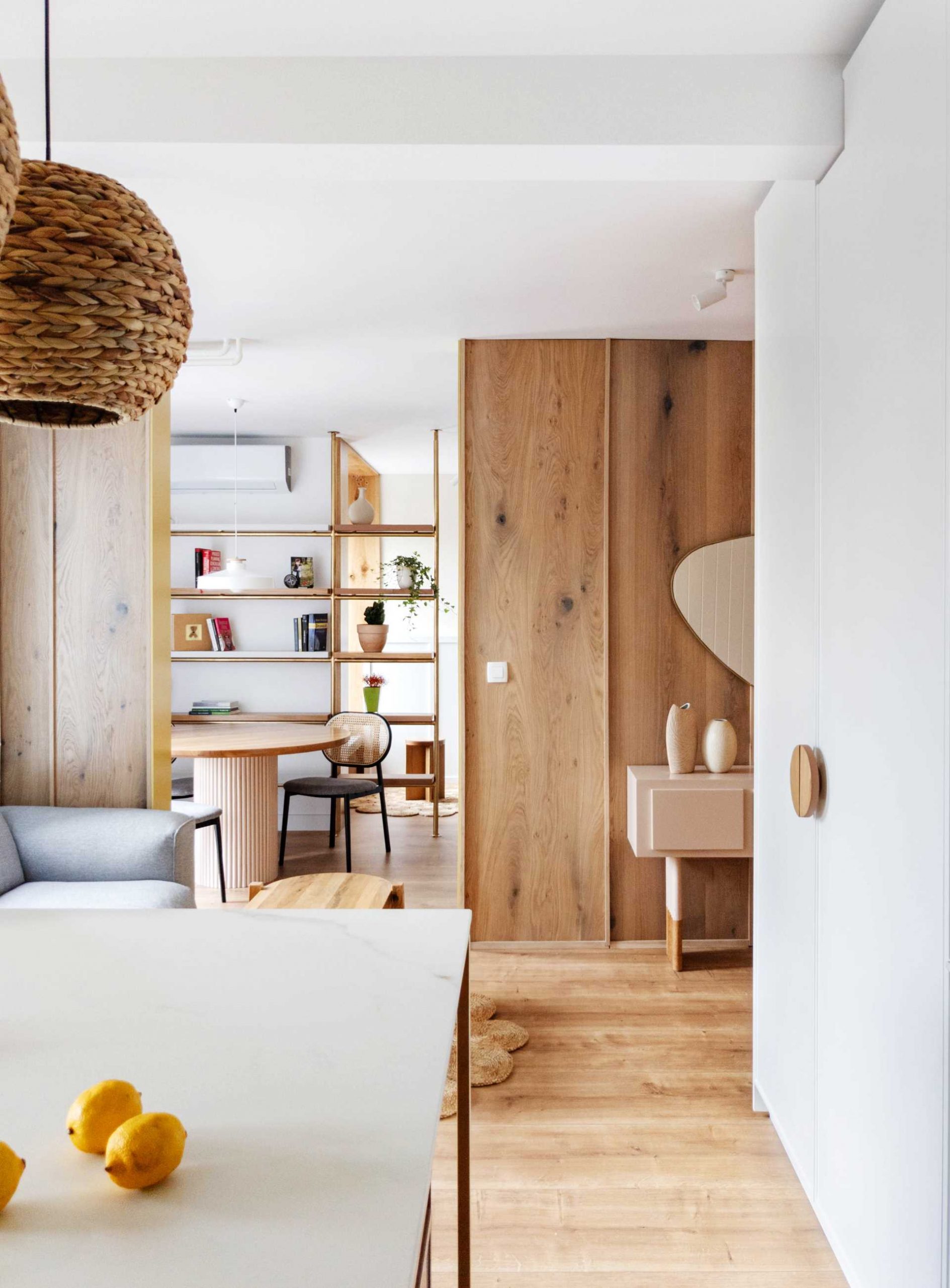 A contemporary dining room with a round table and a metal shelving unit with wood shelves.