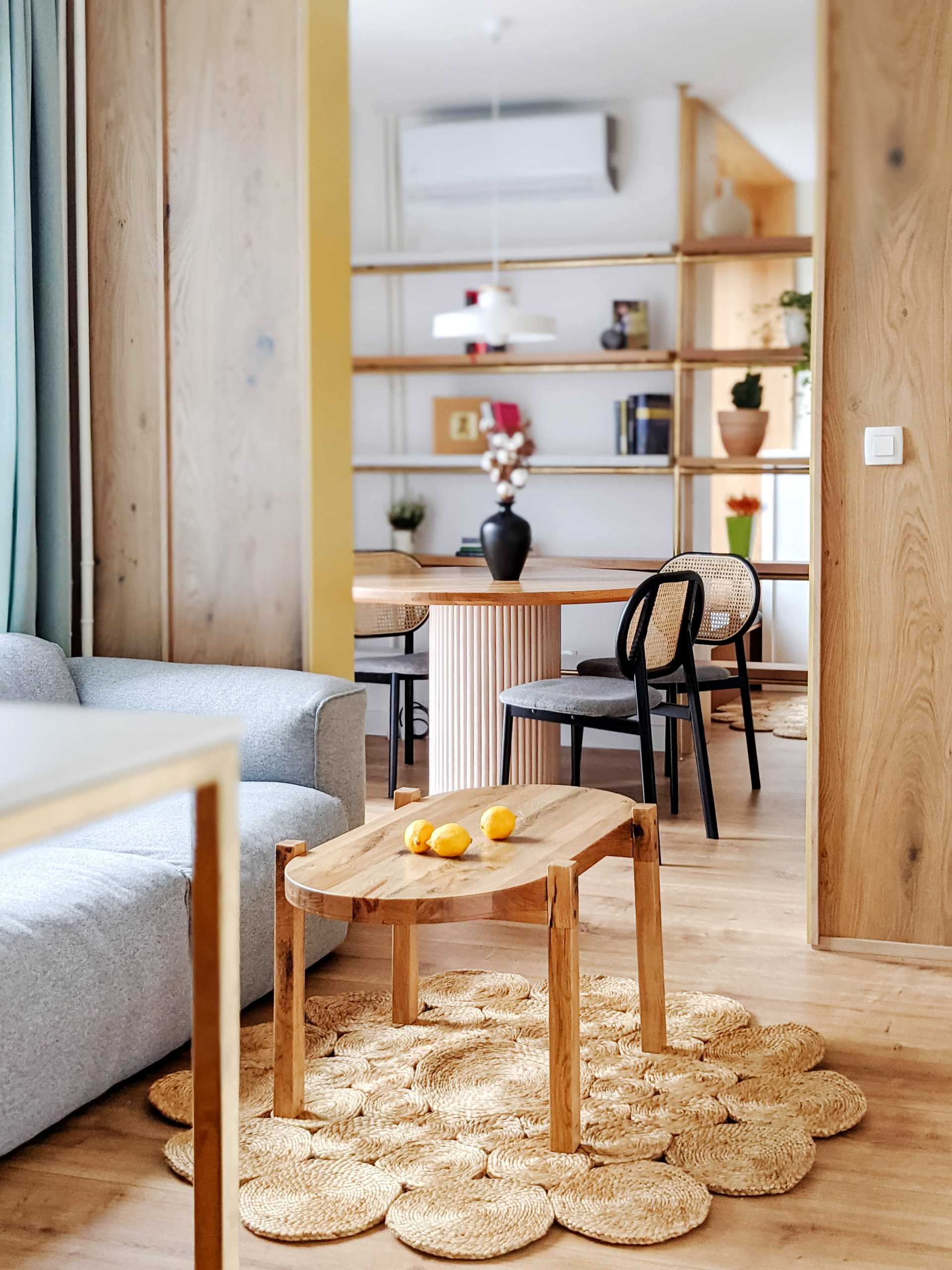 A contemporary dining room with a round table and a metal shelving unit with wood shelves.