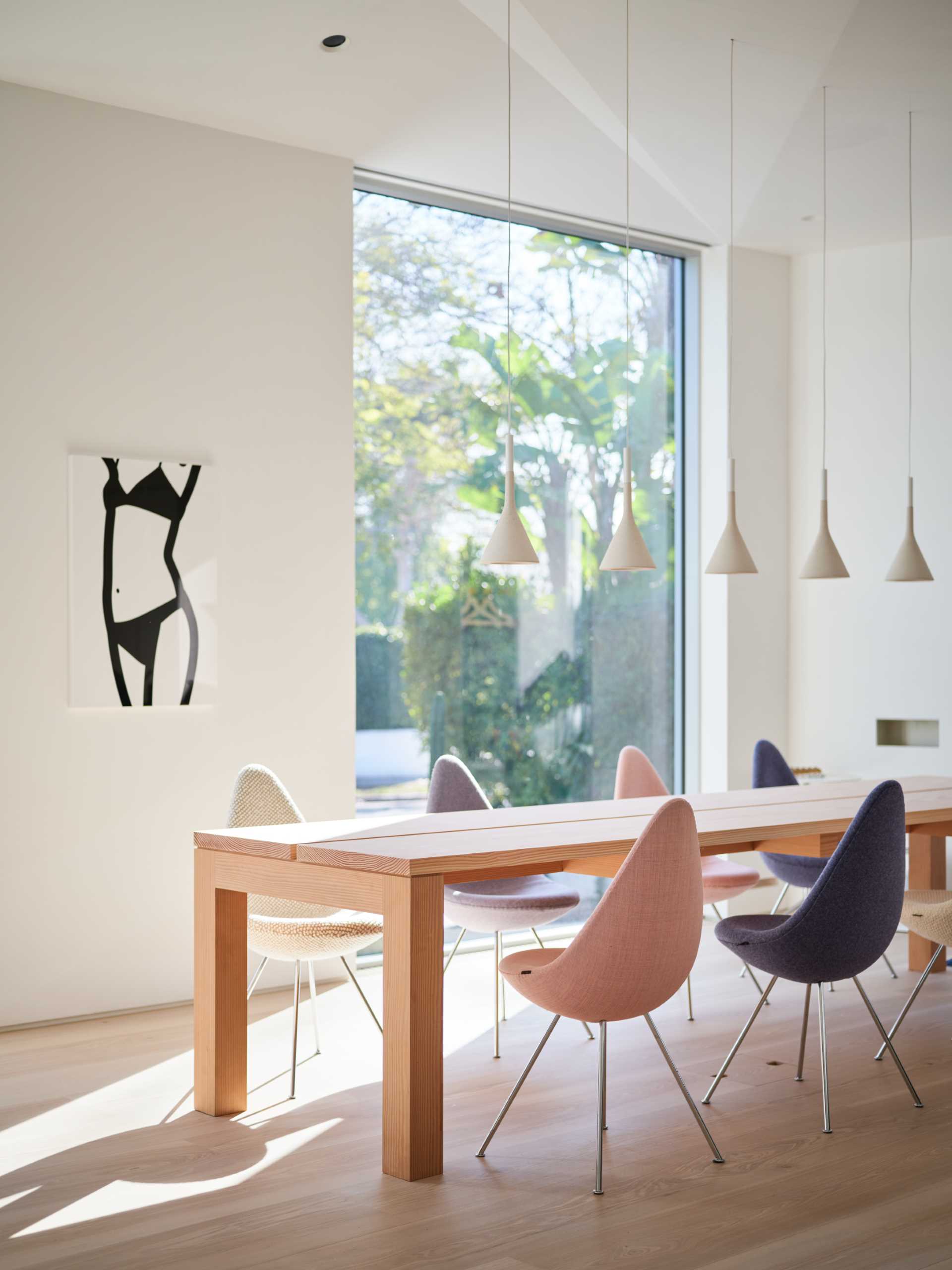 This open plan dining area includes a custom design table made from Douglas Fir planks with a whitewash finish, Foscarini Aplomb pendant lights, and Fritz Hansen Drop Chairs.