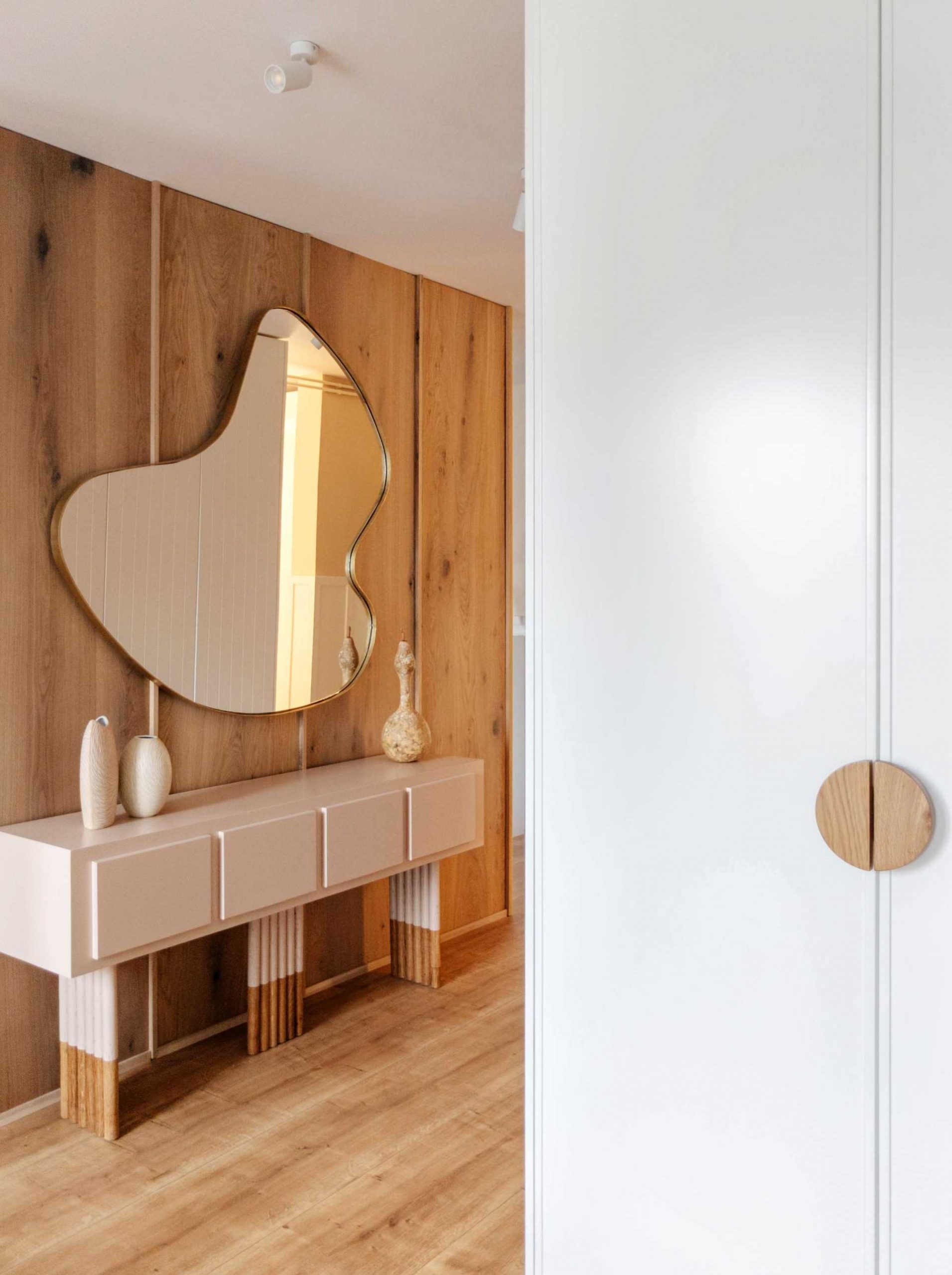 In this hallway, a wood accent wall as well as an abstract mirror and console have been added.