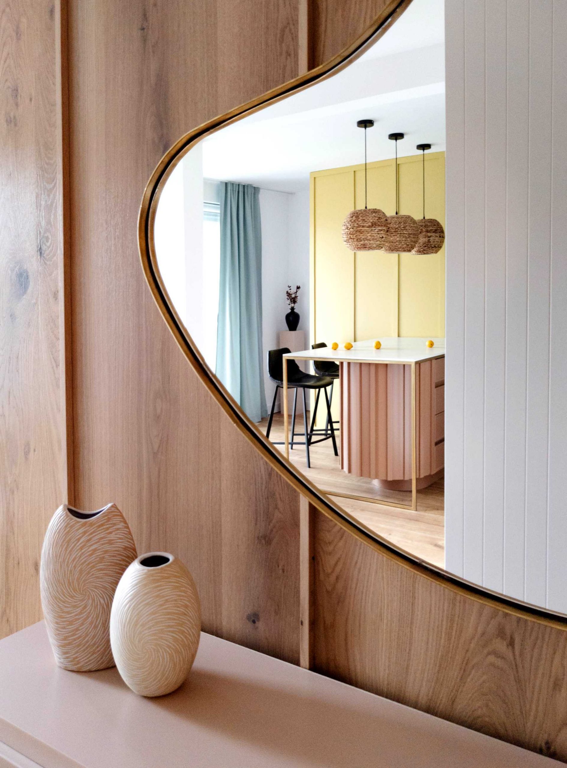 A hallway with a wood accent wall and a abstract mirror shape.