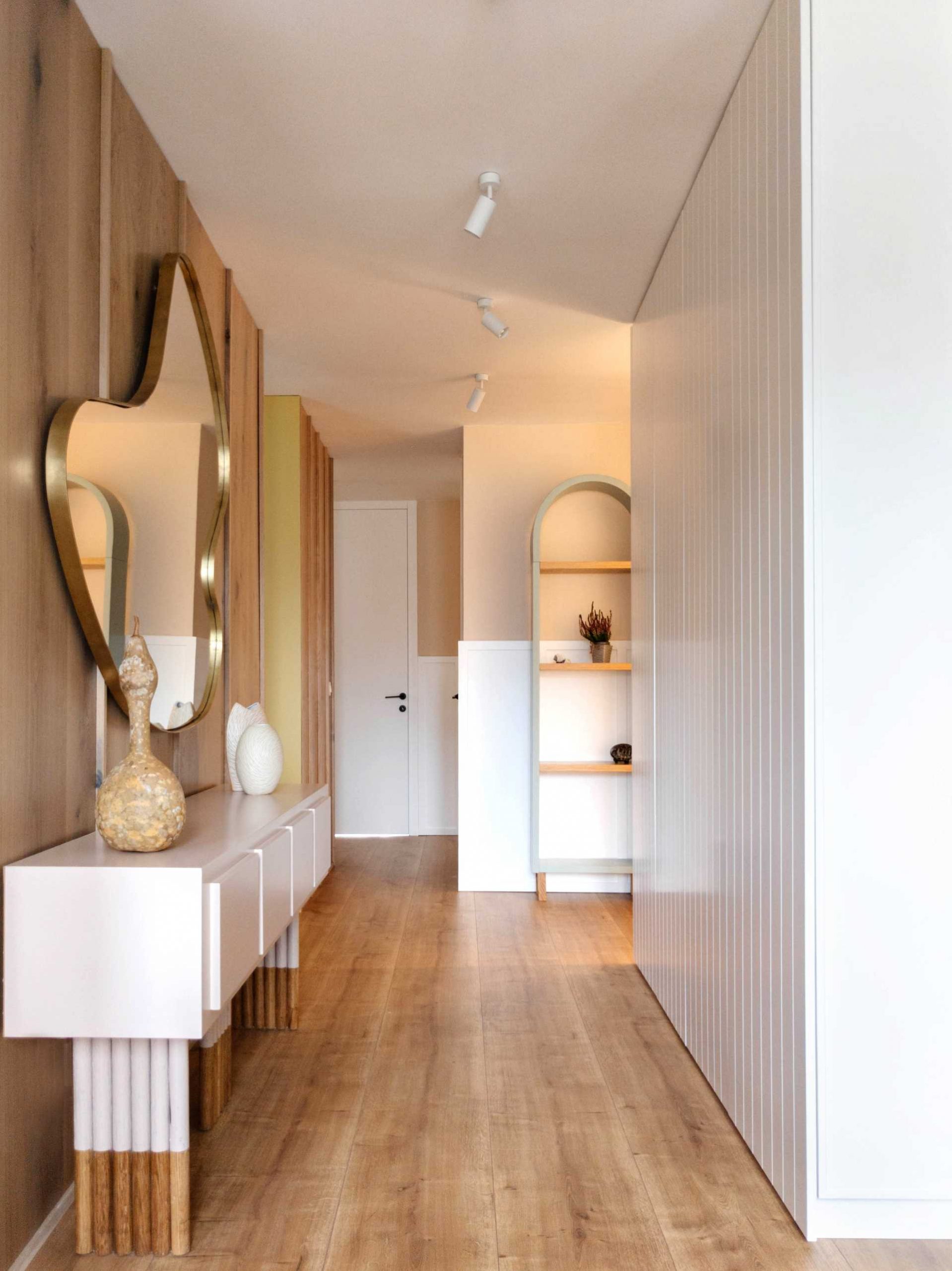 In this hallway, a wood accent wall as well as an abstract mirror and console have been added.