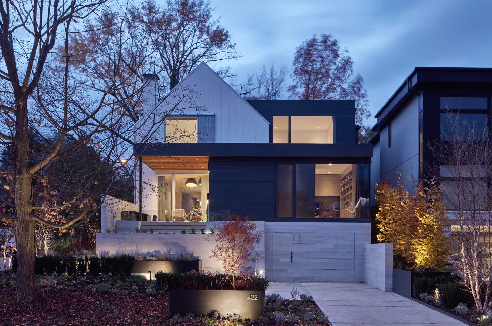 A modern farmhouse inspired home with a two-story white gabled structure and flat-roofed additions on three sides.