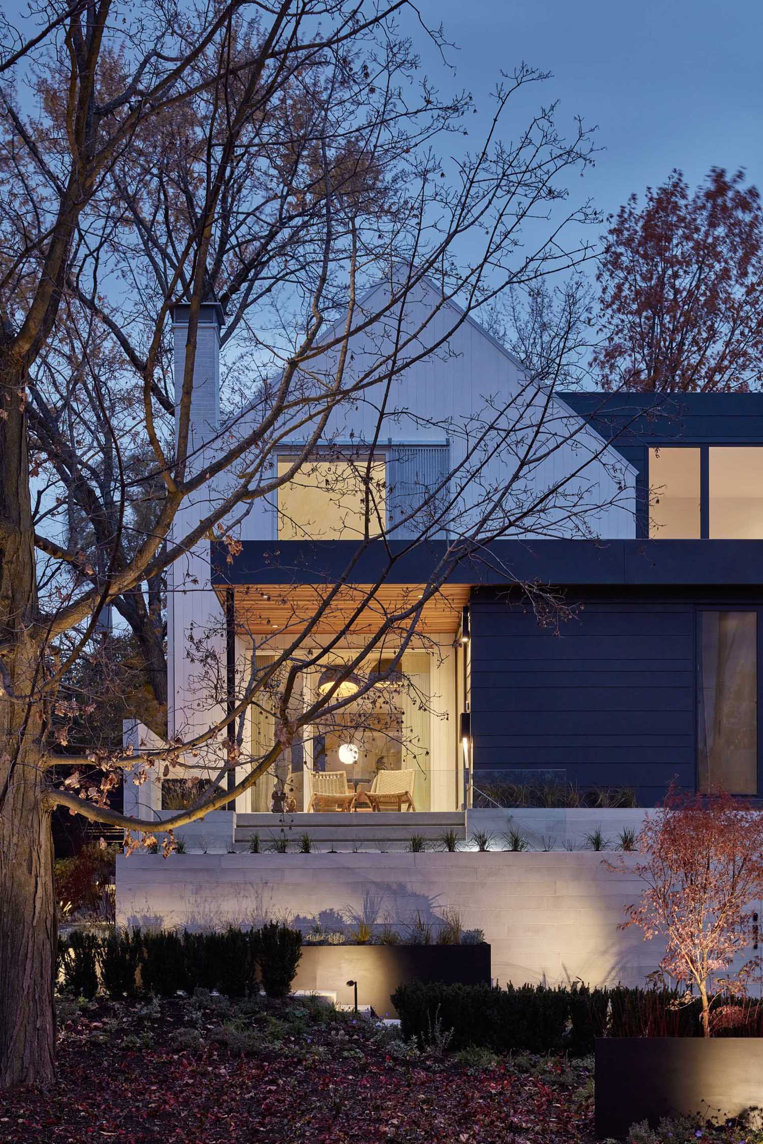 A modern farmhouse inspired home with a two-story white gabled structure and flat-roofed additions on three sides.