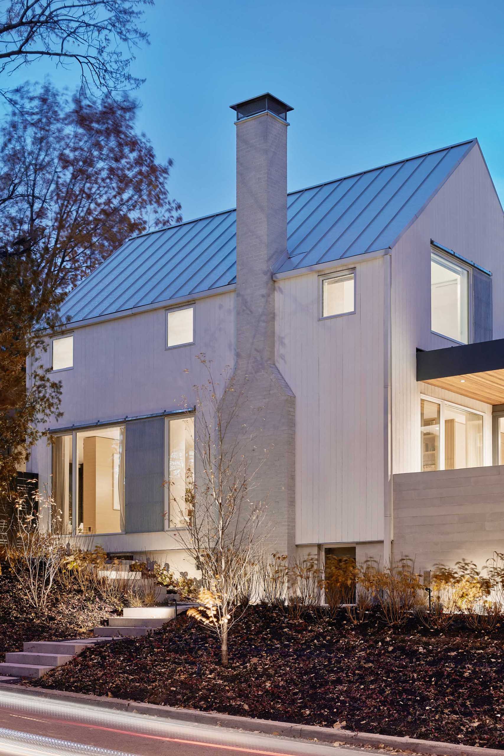 A modern farmhouse inspired home with a two-story white gabled structure and flat-roofed additions on three sides.