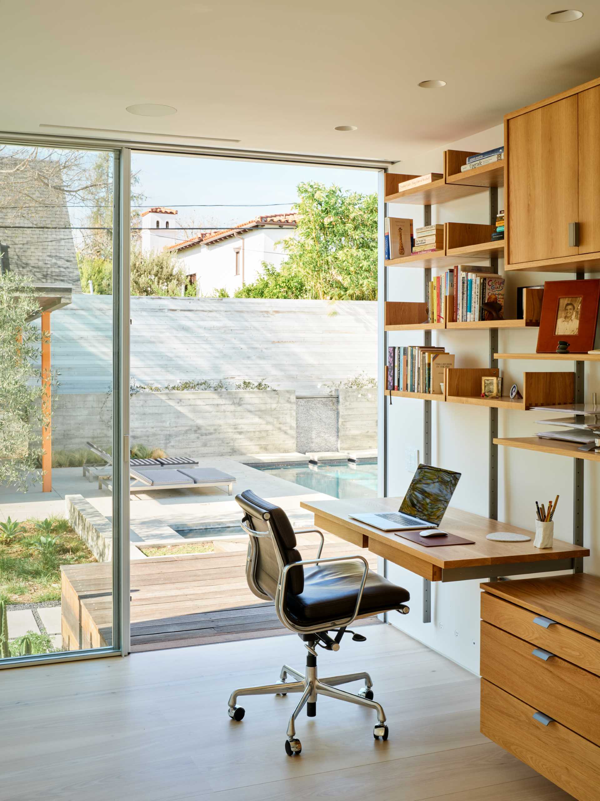 A modern home office with a wall mounted desk and wood shelving.