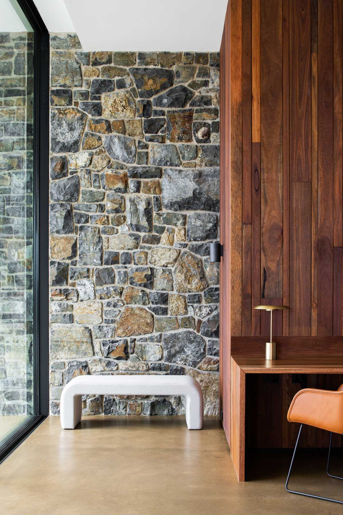 A modern home with stone walls, a seating area, and a built-in wood desk.
