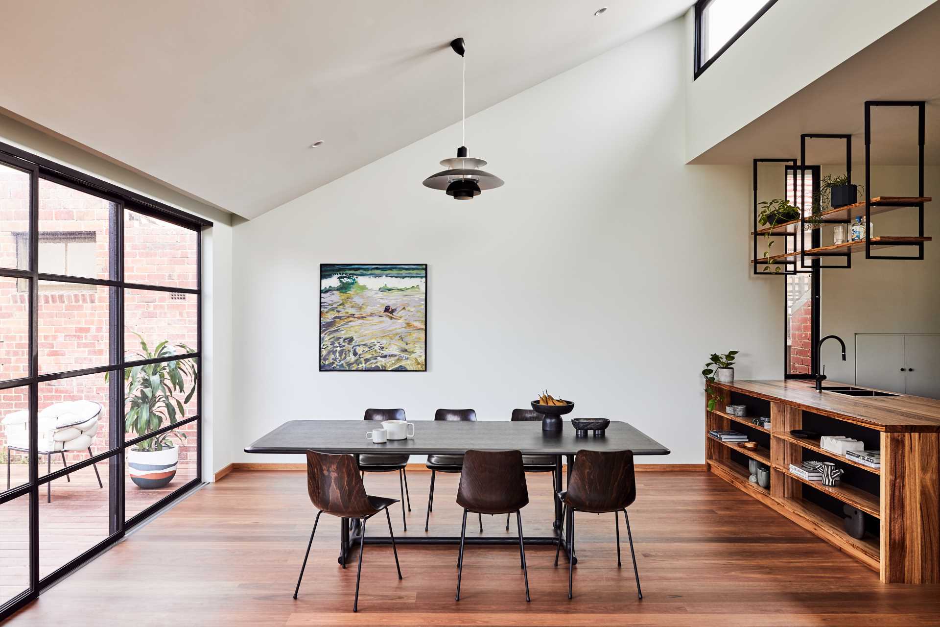 The matte black framed steel sliding glass door, as well as clerestory windows, flood this modern dining area with natural light.