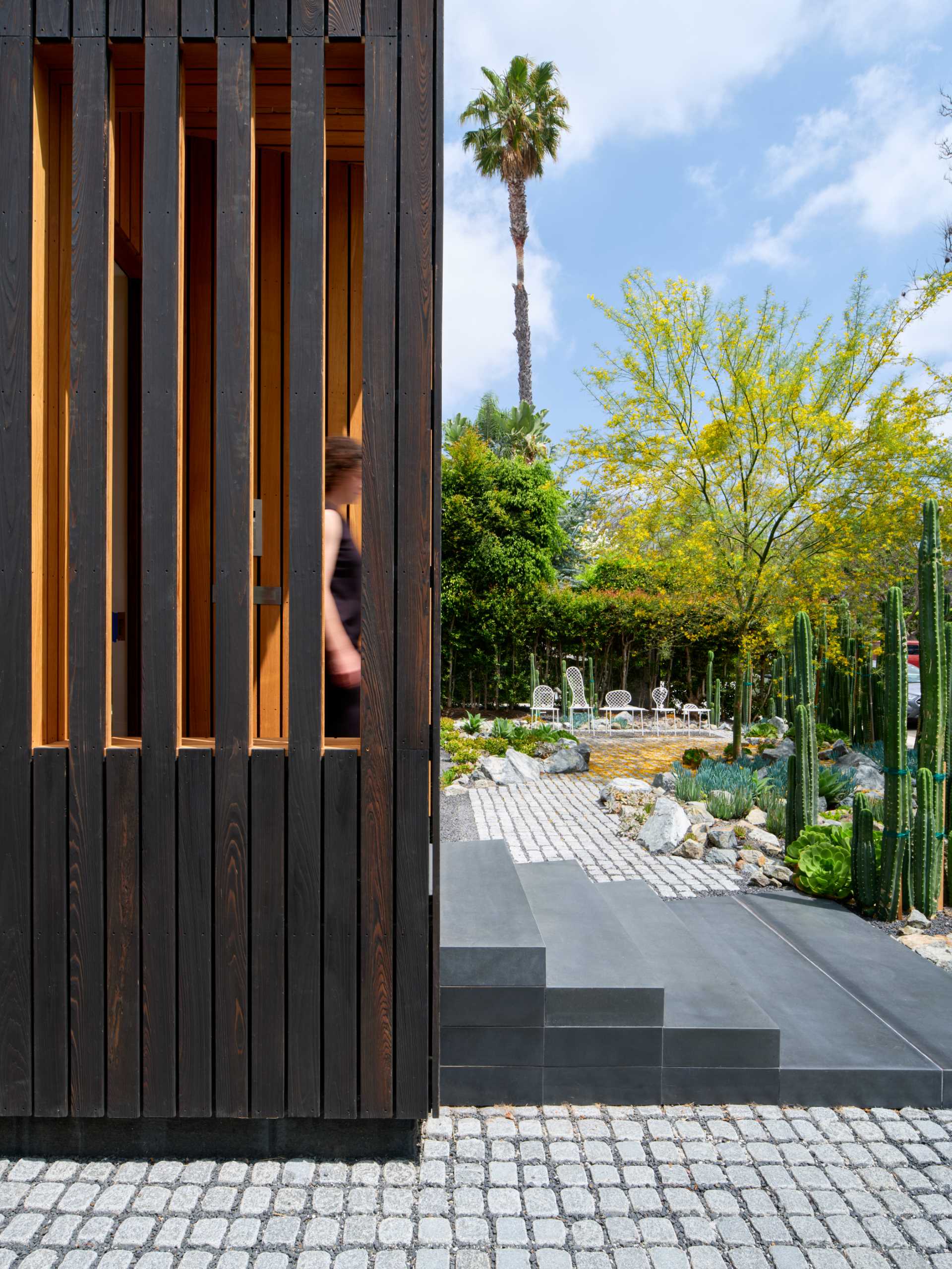 This modern house has a cacti garden, that includes some succulents, and provides privacy for the home, without hiding the view of the street. A small patio with seating makes use of the low maintenance front garden.