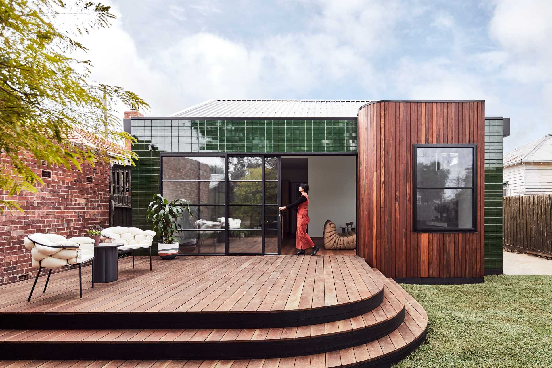 A modern house addition with glazed green tiles and vertical wood siding.