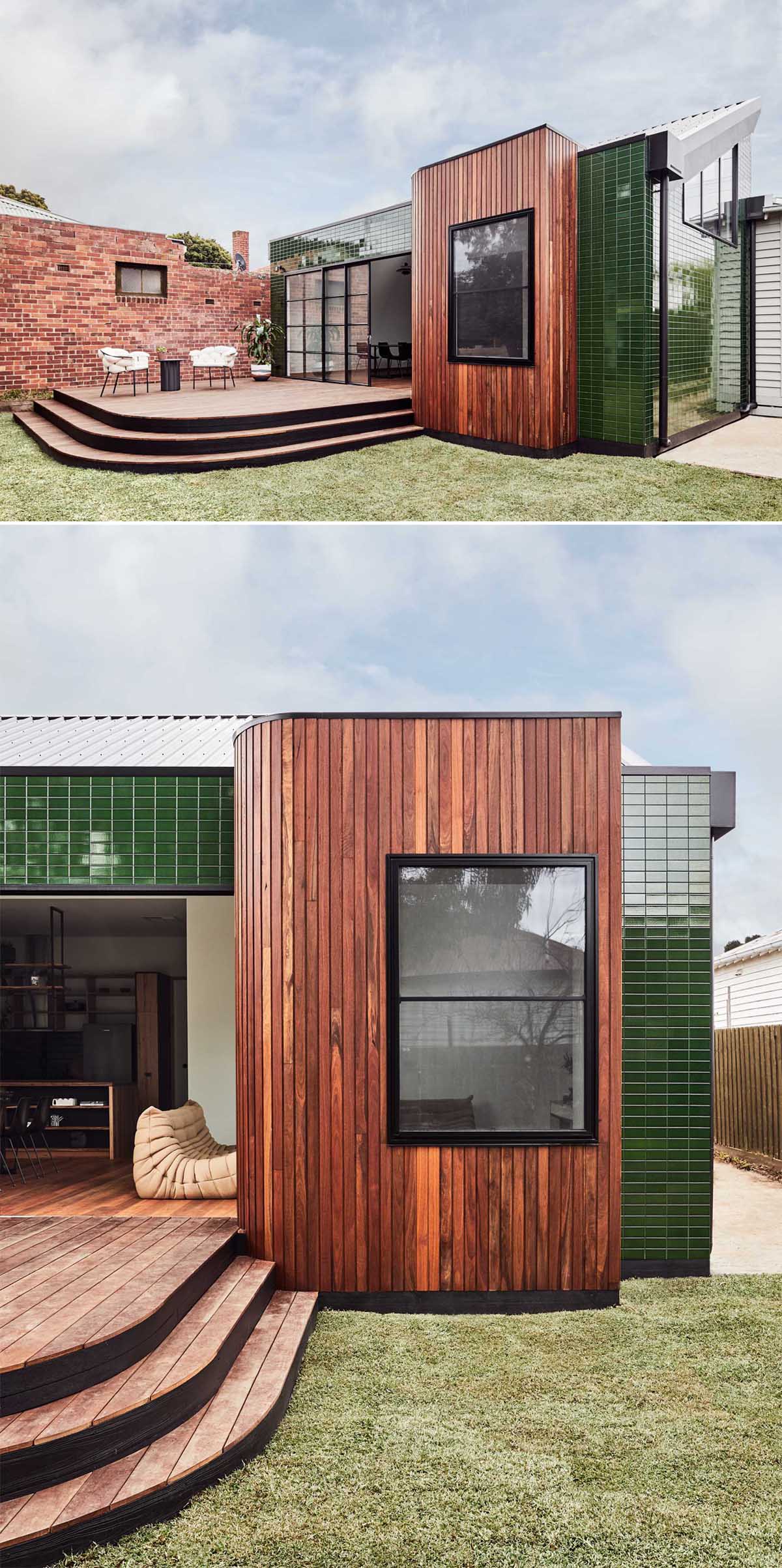 A modern house addition with glazed green tiles, vertical wood siding, and a deck.