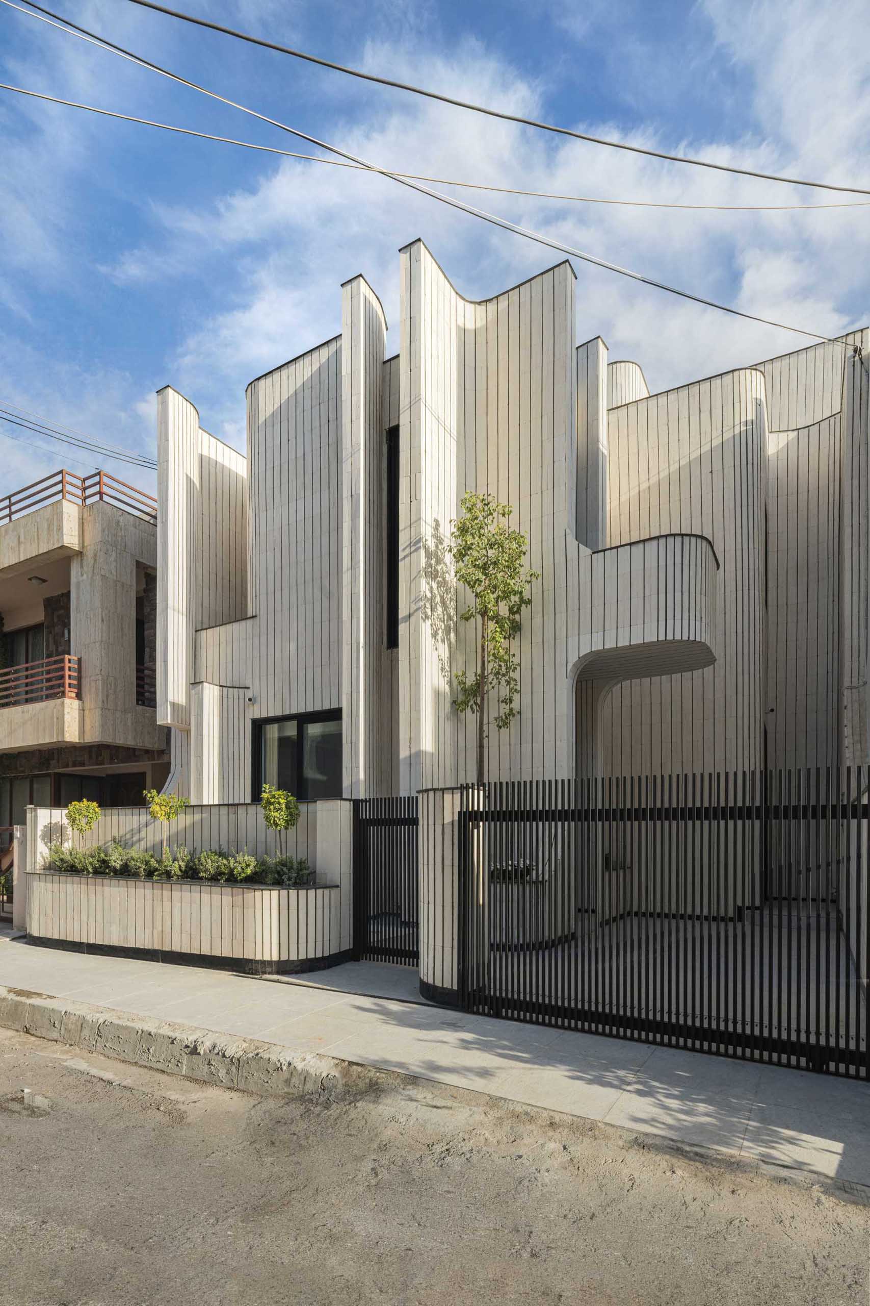 A modern sculptural house covered in tiles with built-in planters.