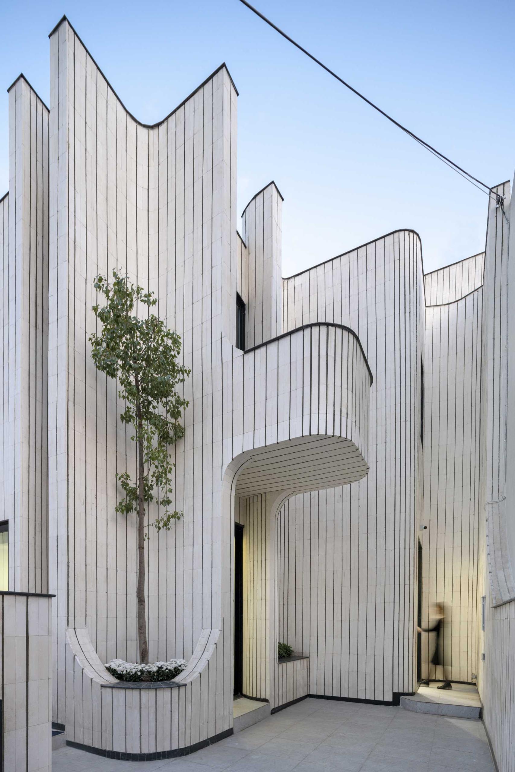 This modern house is covered in tiles, giving it a unique appearance on the street.