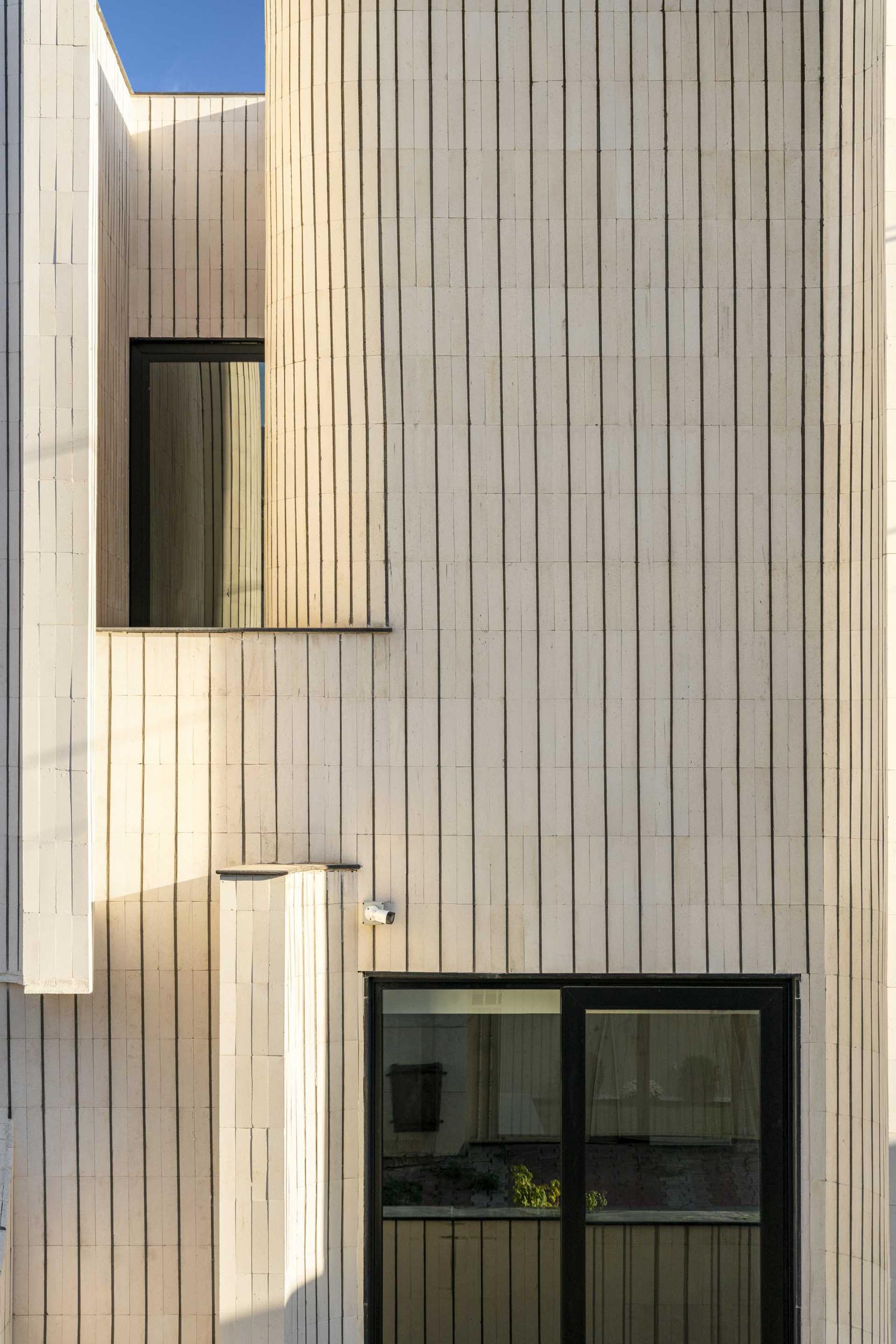 The sculptural form of this modern house is covered in tiles, giving it a unique appearance on the street.