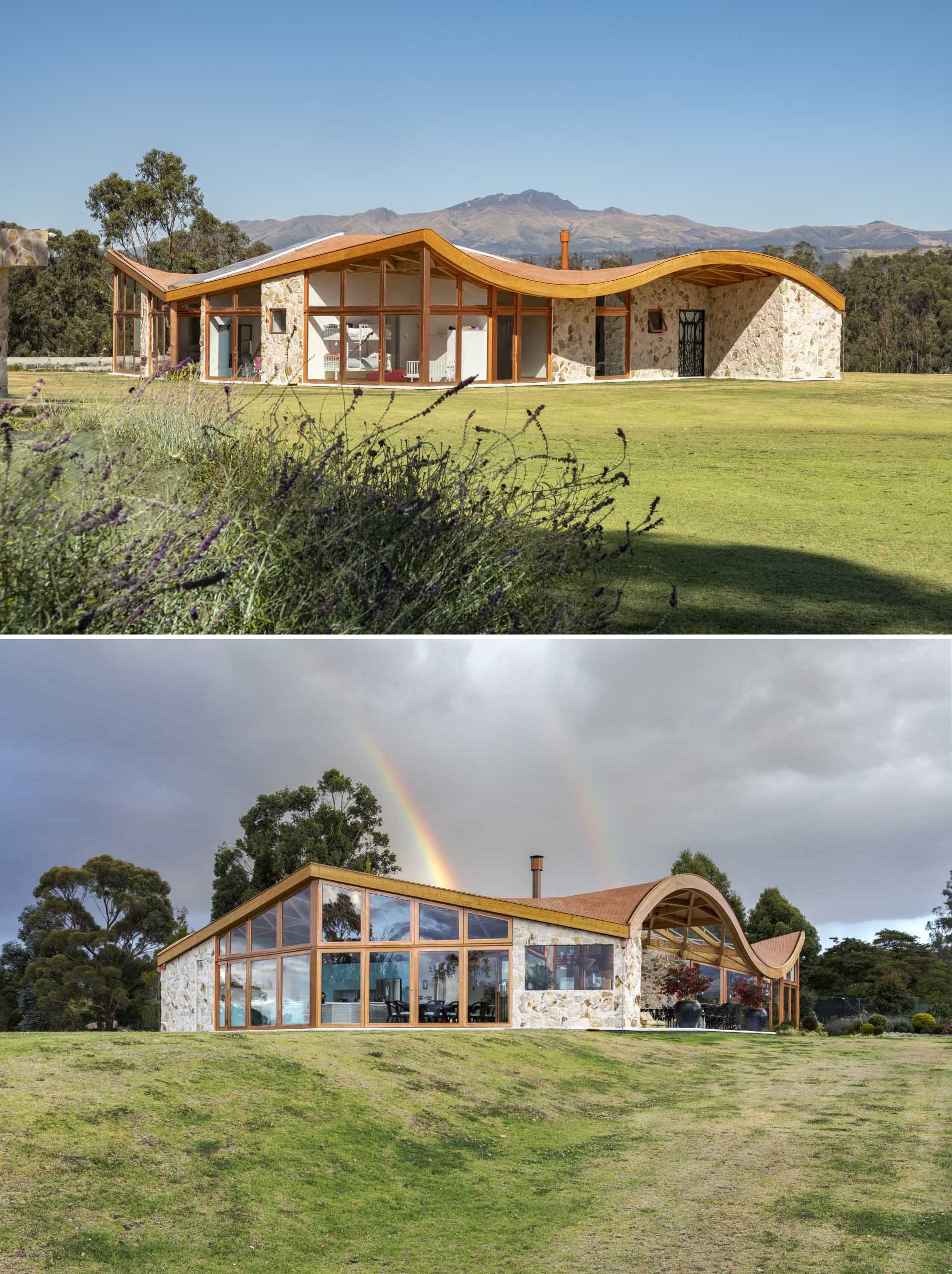 A modern wood and stone house with glass walls and a wavy roof.