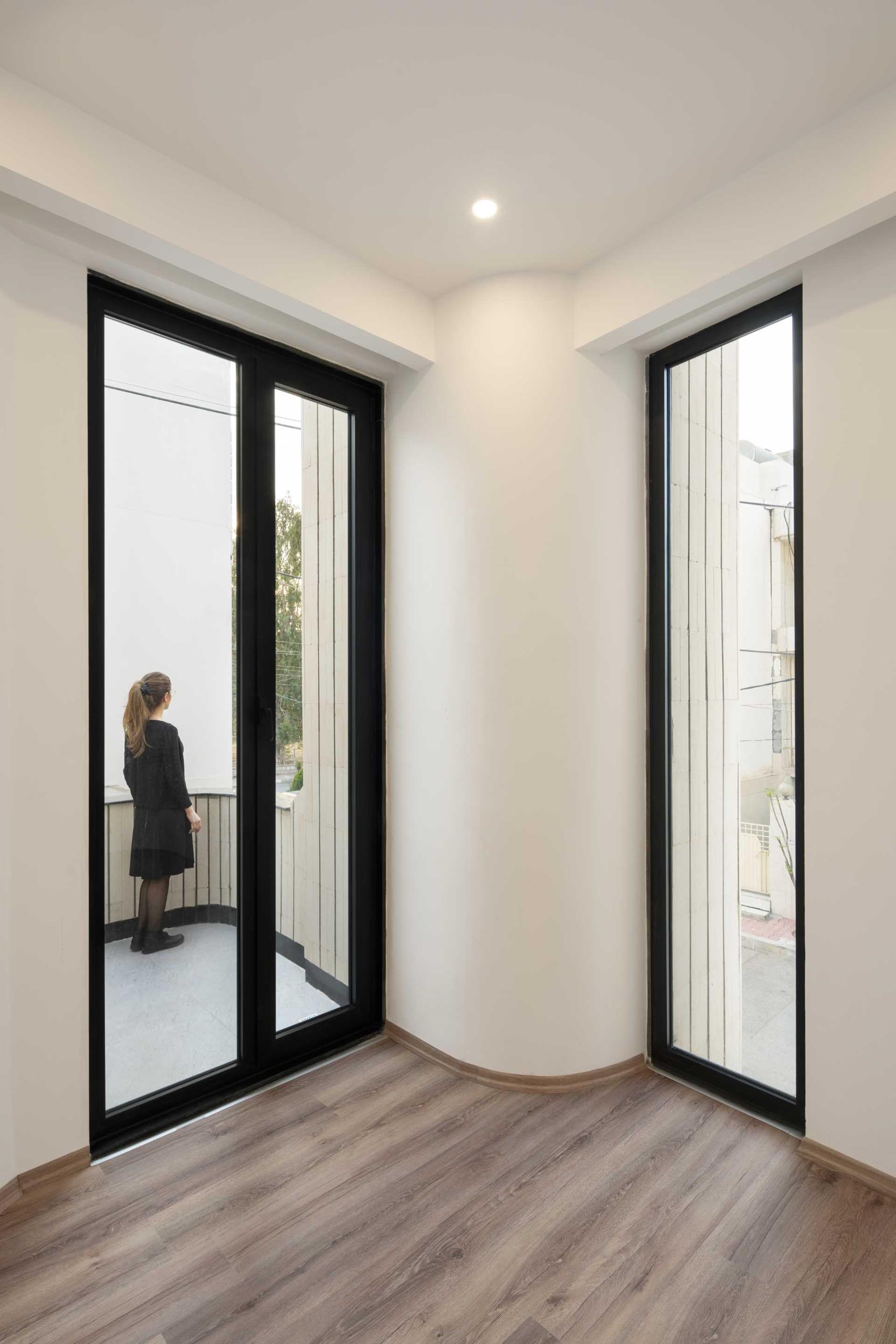 A modern home with wood floors, white walls, and black window and door frames.