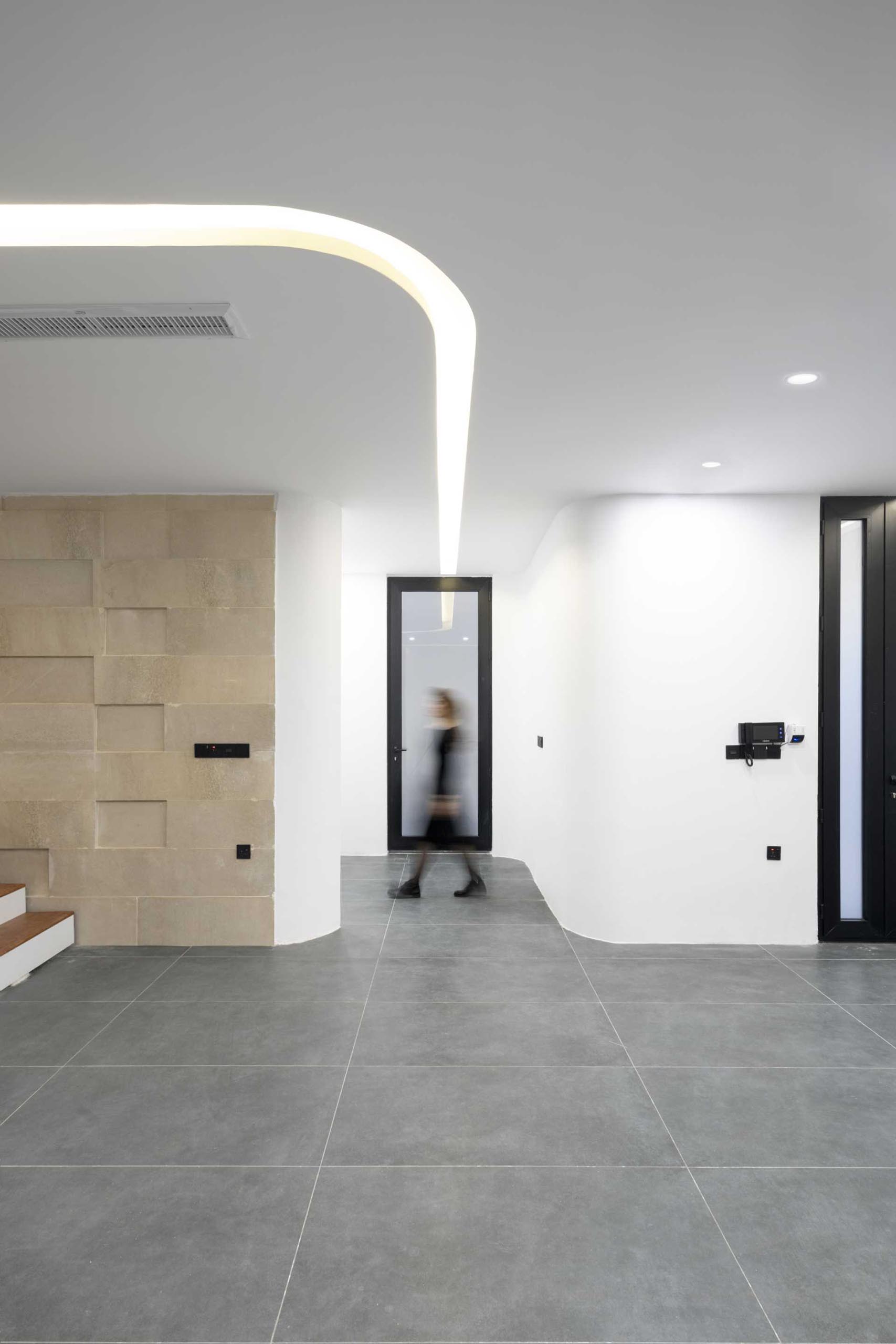 A modern house with grey tile flooring and curved lighting.