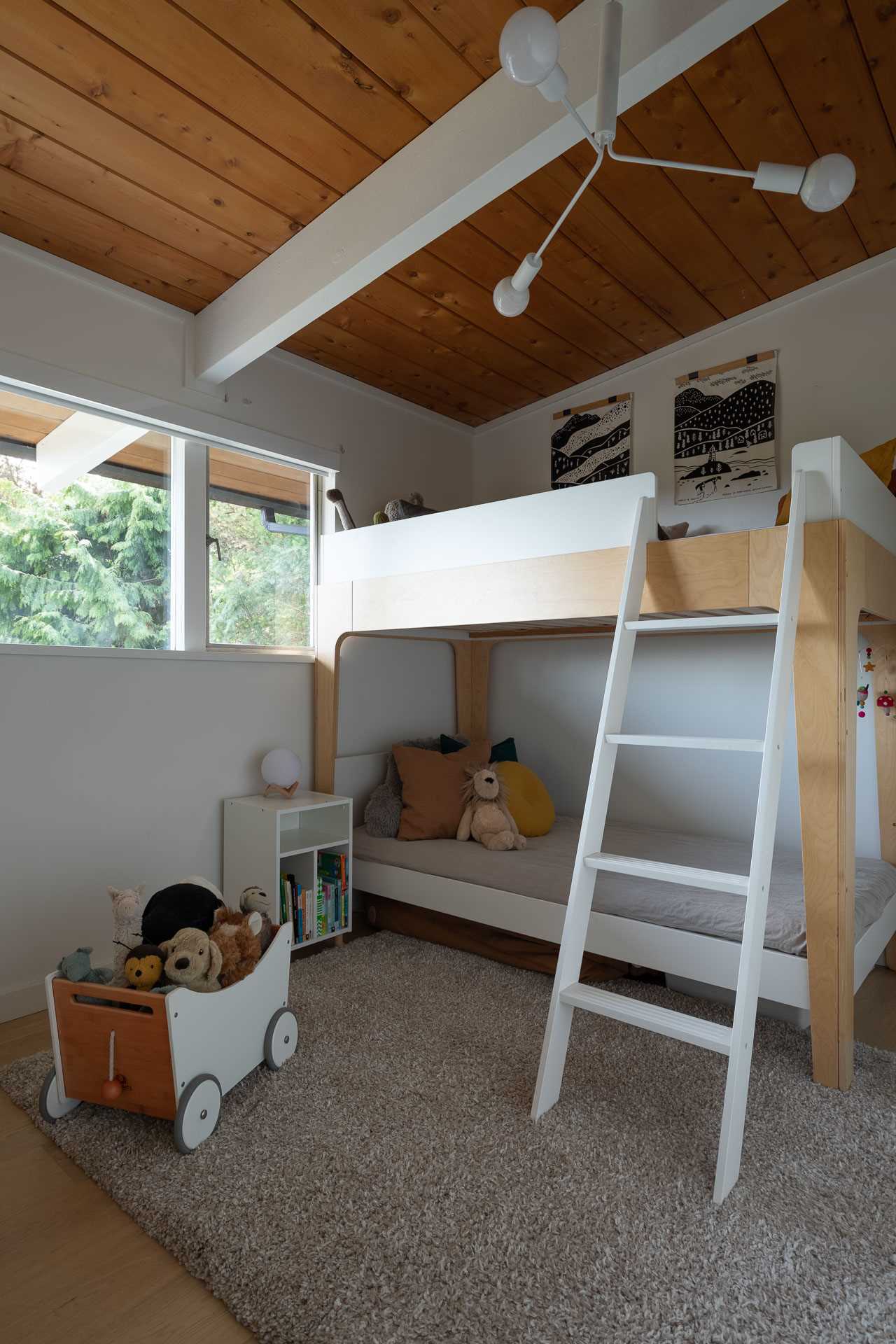 This updated kids bedroom includes white walls, matching the white painted beams and ceiling light, while a bunk bed makes the most of the space.