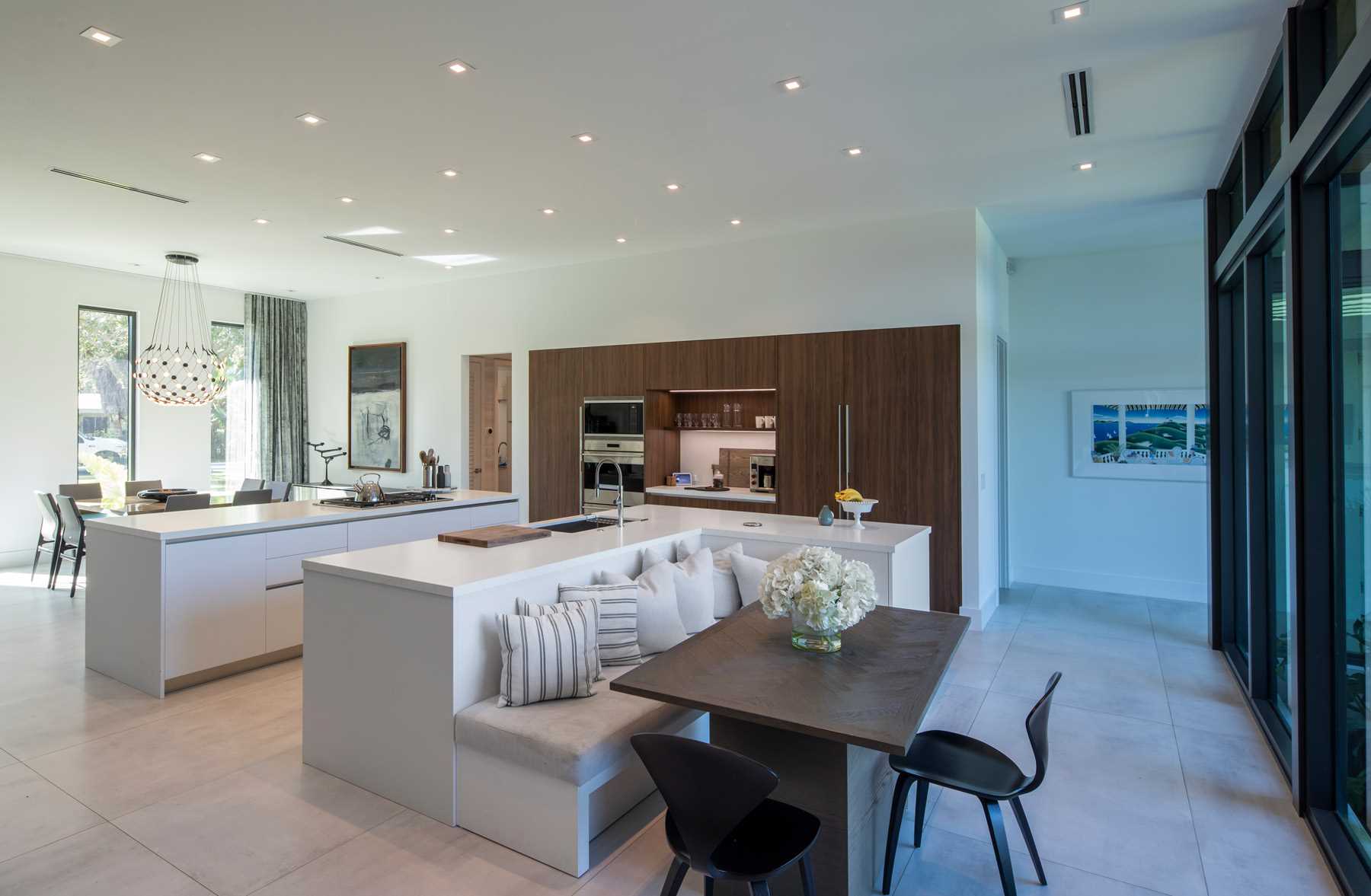 A modern kitchen with two islands, and one has a dropped down section that acts as banquette seating for a casual dining experience.