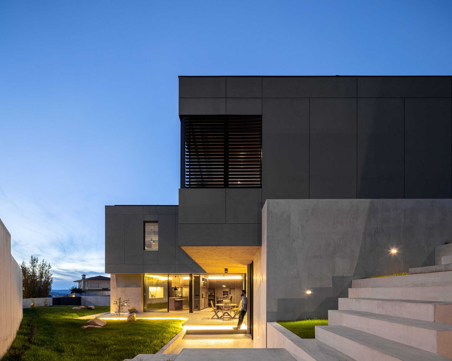 A modern house with exterior lighting highlights the yard.