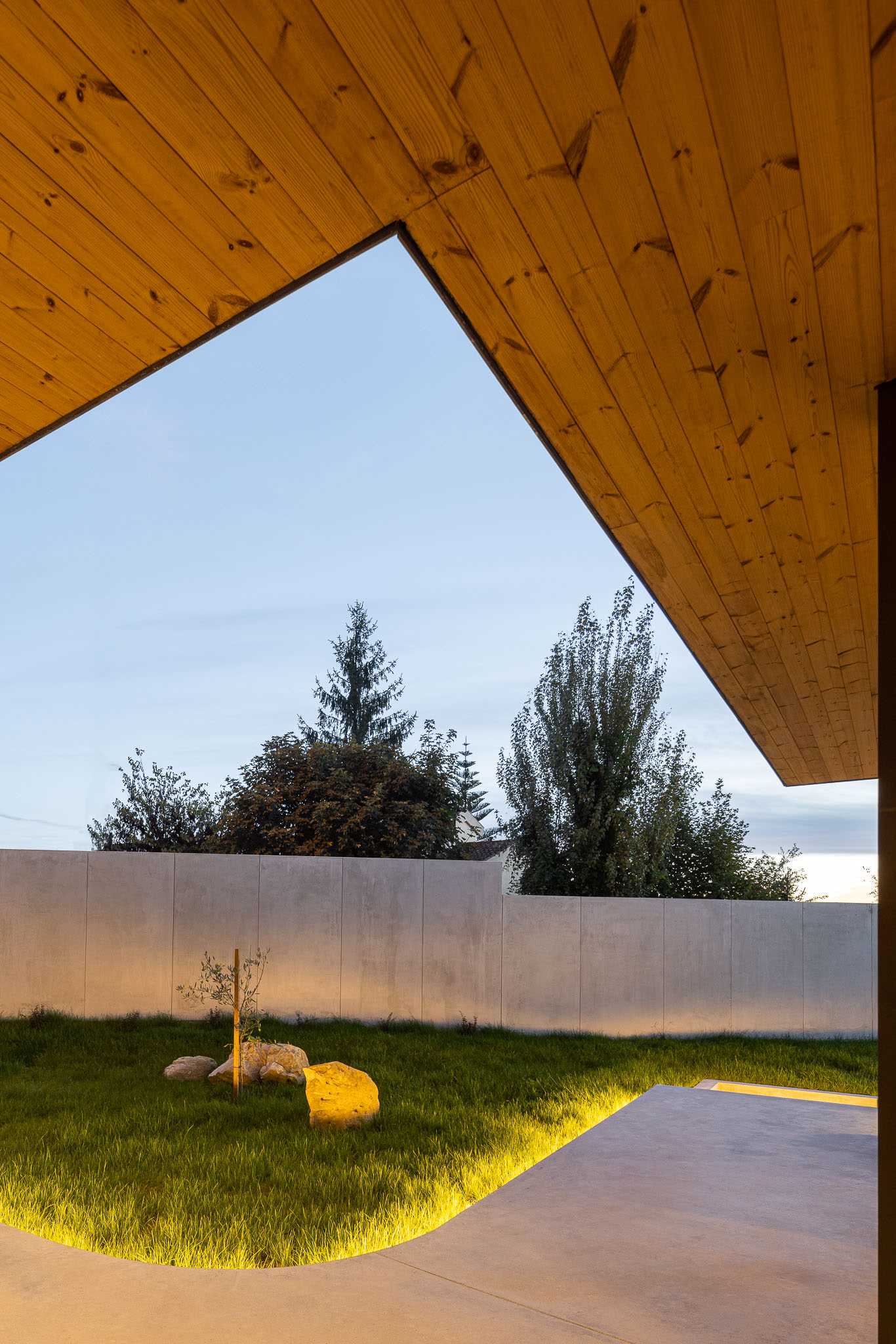 A modern concrete patio with hidden lighting that lights up the lawn and boulders.