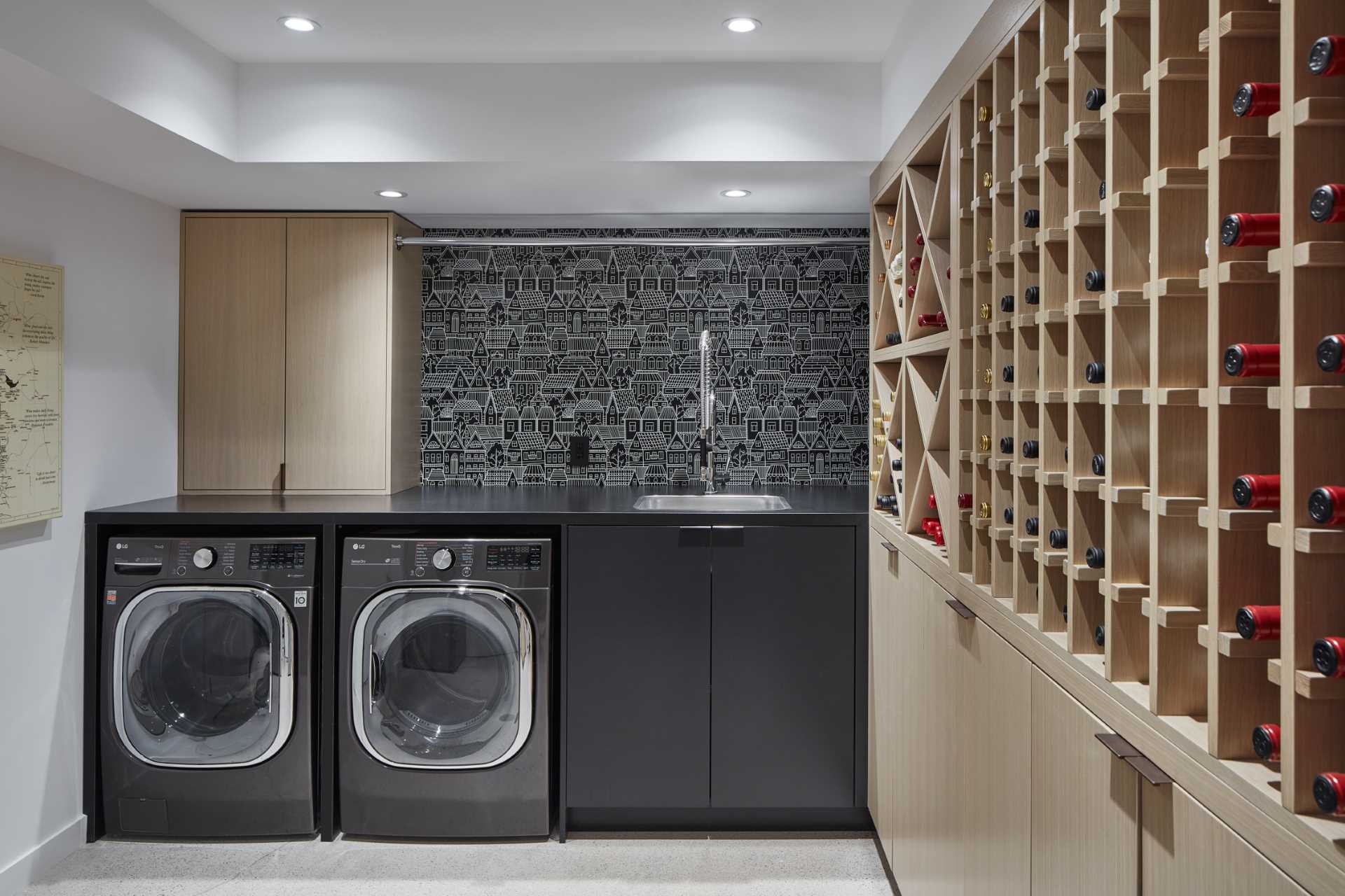 A large laundry room includes custom cabinetry that houses the laundry machines, while the adjacent wall is dedicated to storage and wine storage.