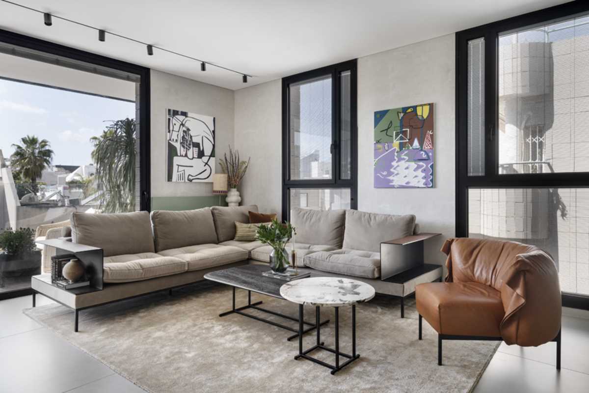 A modern living room furnished with a corner couch, a brown leather chair, and a pair of coffee tables.