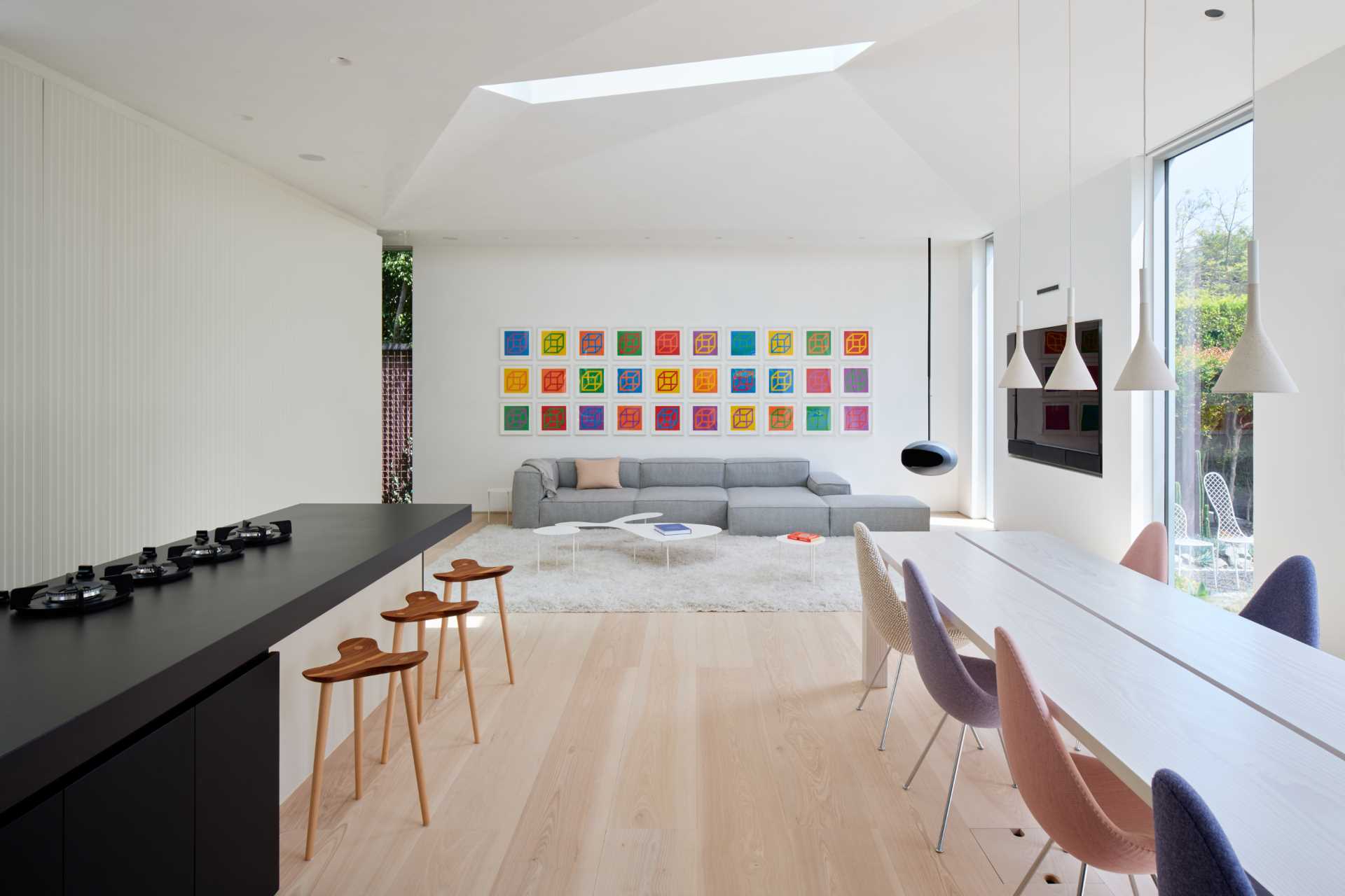 This spacious, light-flooded living room has colorful artwork by Sol LeWitt and a Cocoon Aeris suspended black fireplace.