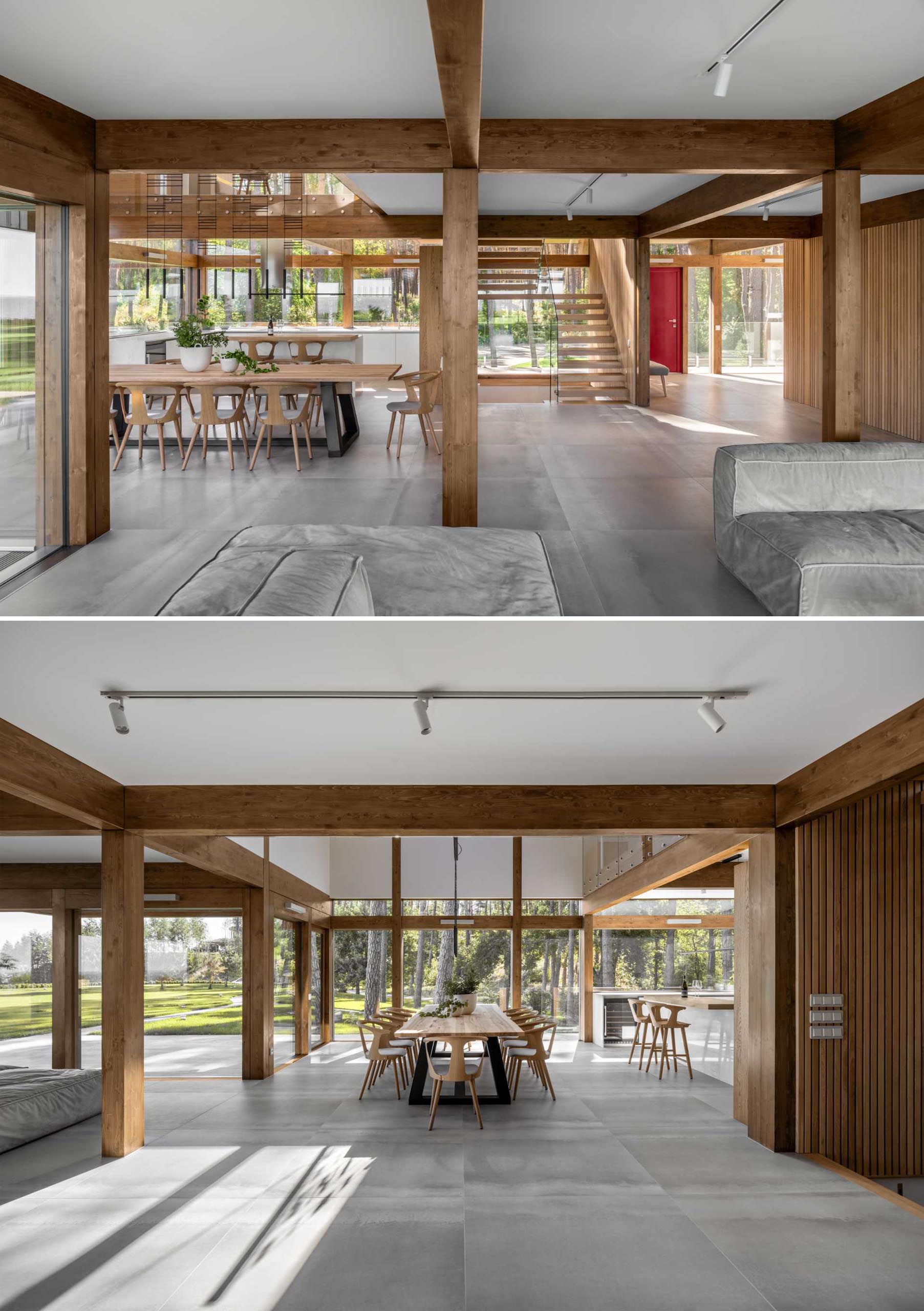 This open plan dining room includes a large 10 person wood table with black legs. A skylight and minimalist light fixture draws attention to the the double-height ceiling above.