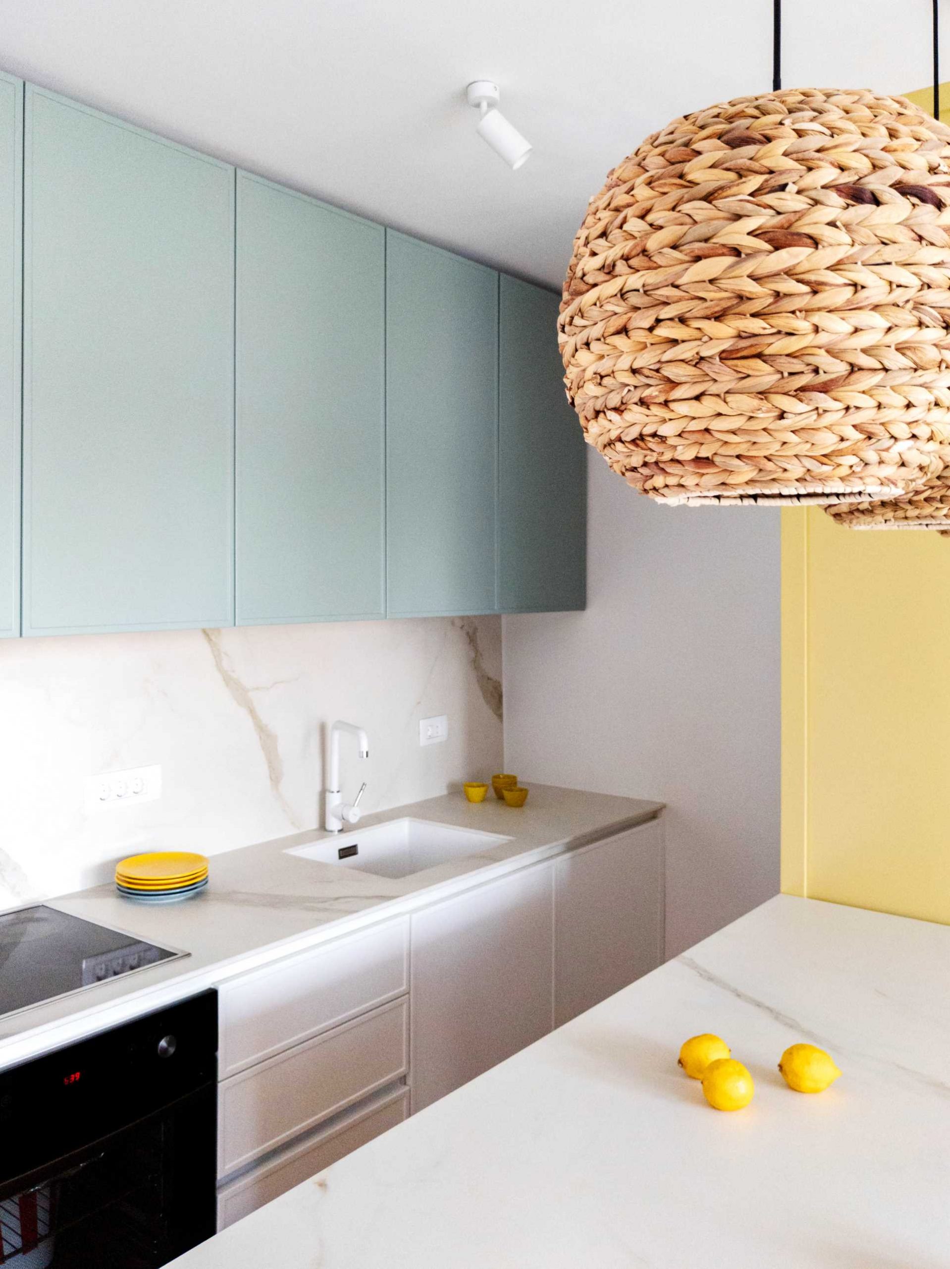 Pastel colors have been used to brighten up this contemporary kitchen, with a yellow accent wall and muted mint green for the upper cabinets.