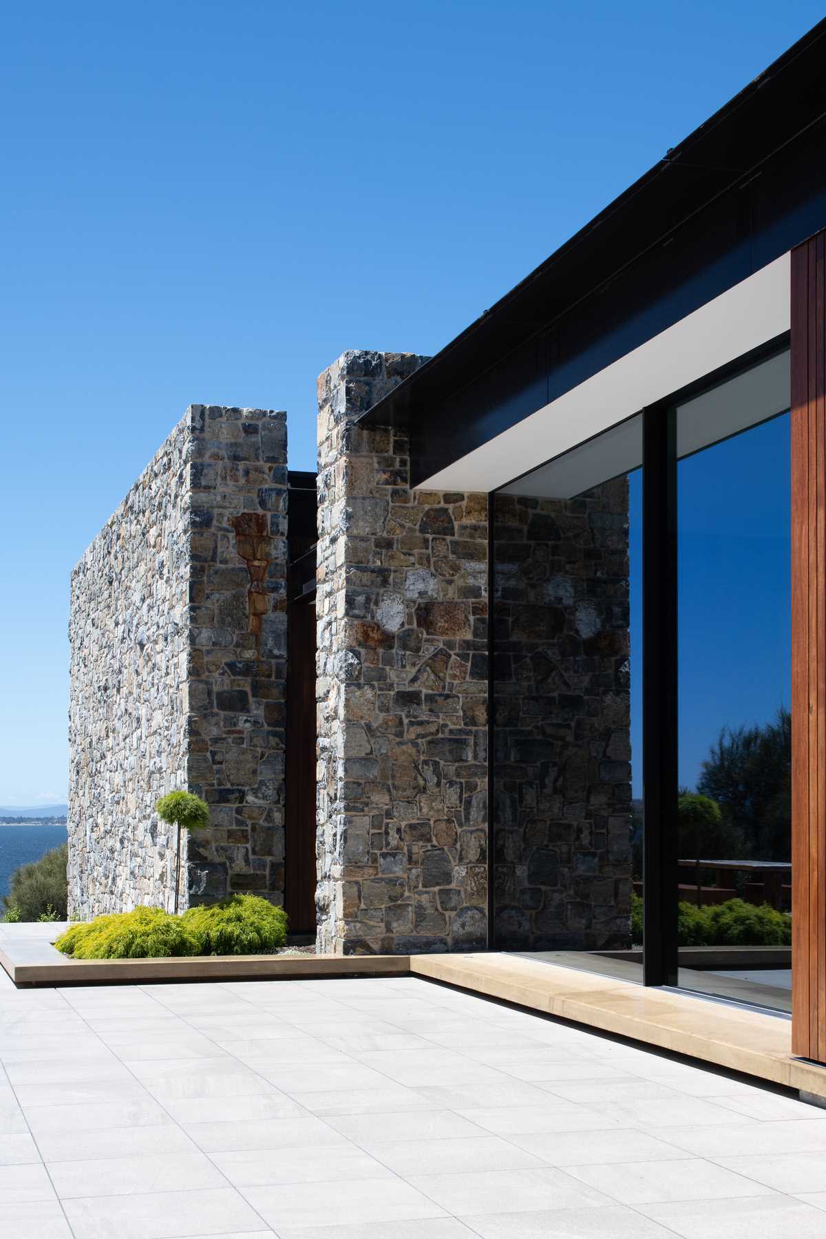 A modern house with stone walls, and wood and black steel accents.