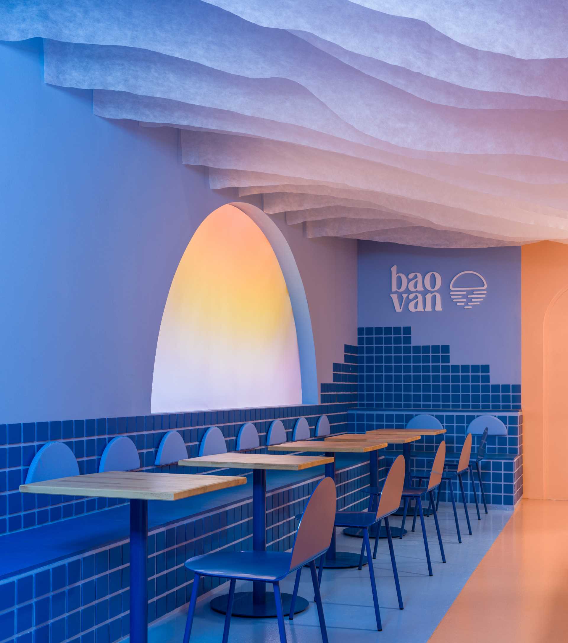 A modern restaurant inspired by a beach sunset, includes a custom light screen that changes colors.